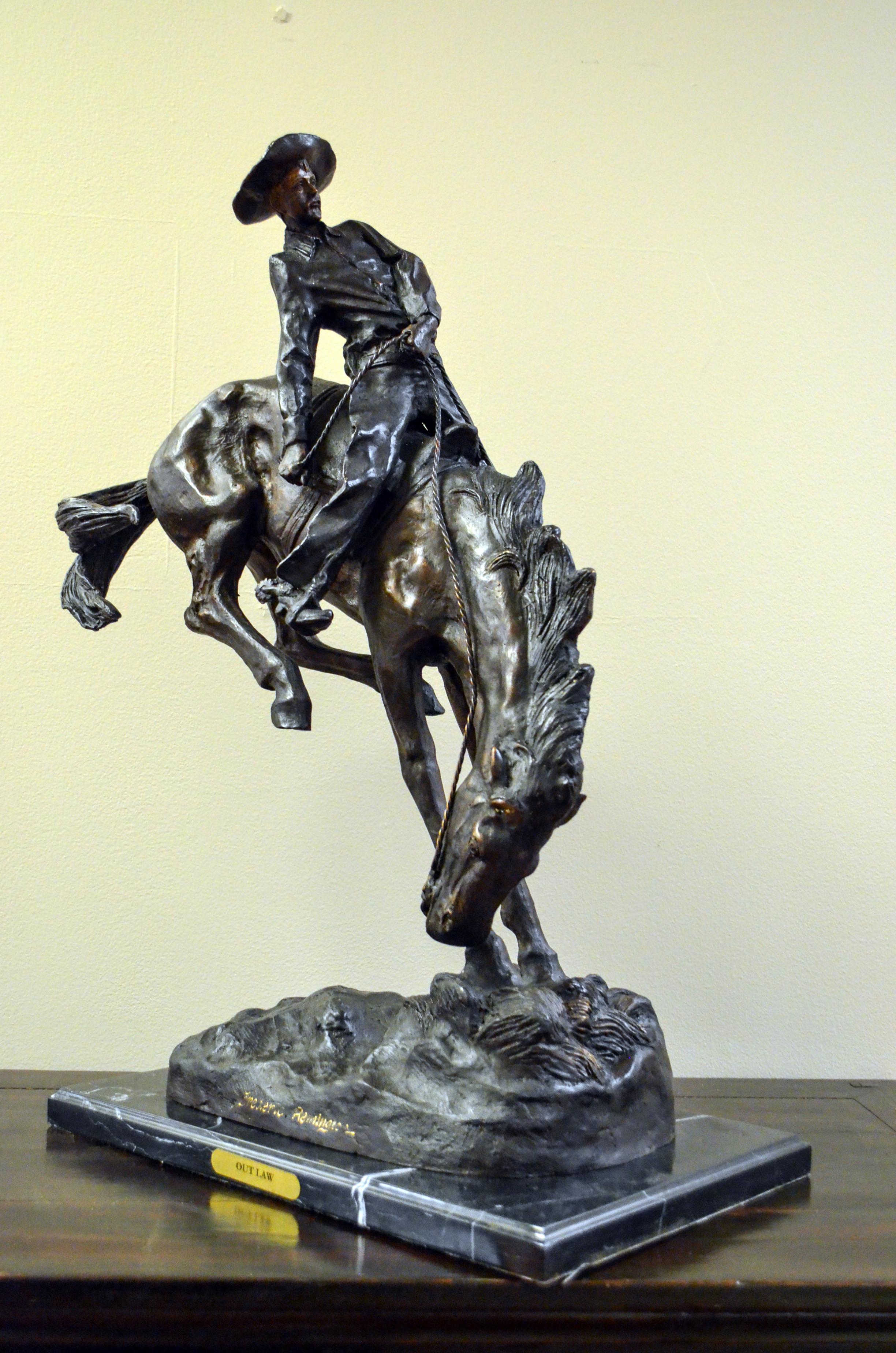 Outlaw, a cast bronze sculpture after American artist Frederic Remington's 1906 original, on marble base. Filled with a tremendous dramatic tension, this bronze sculpture depicts a scene from the American Old West particularly dear to Frederic