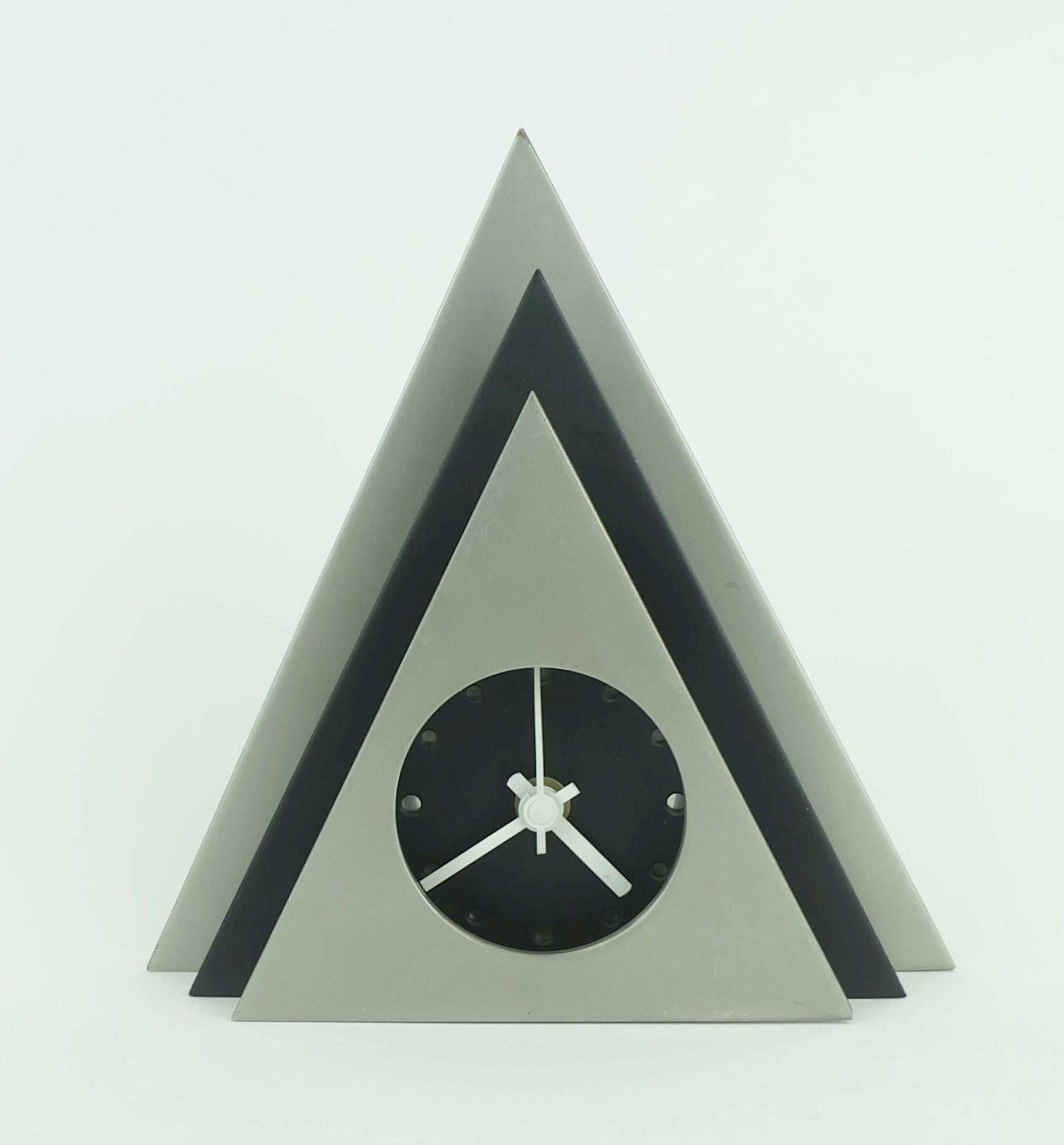 Reloj de sobremesa de los años 80 de diseño excepcional. De metal lacado en negro y gris plateado, agujas de reloj blancas. Funciona con pilas (la pila no está incluida).

Dimensiones en cm: 
Anchura 19,9 cm, altura 20,4 cm, profundidad 4,5 cm.