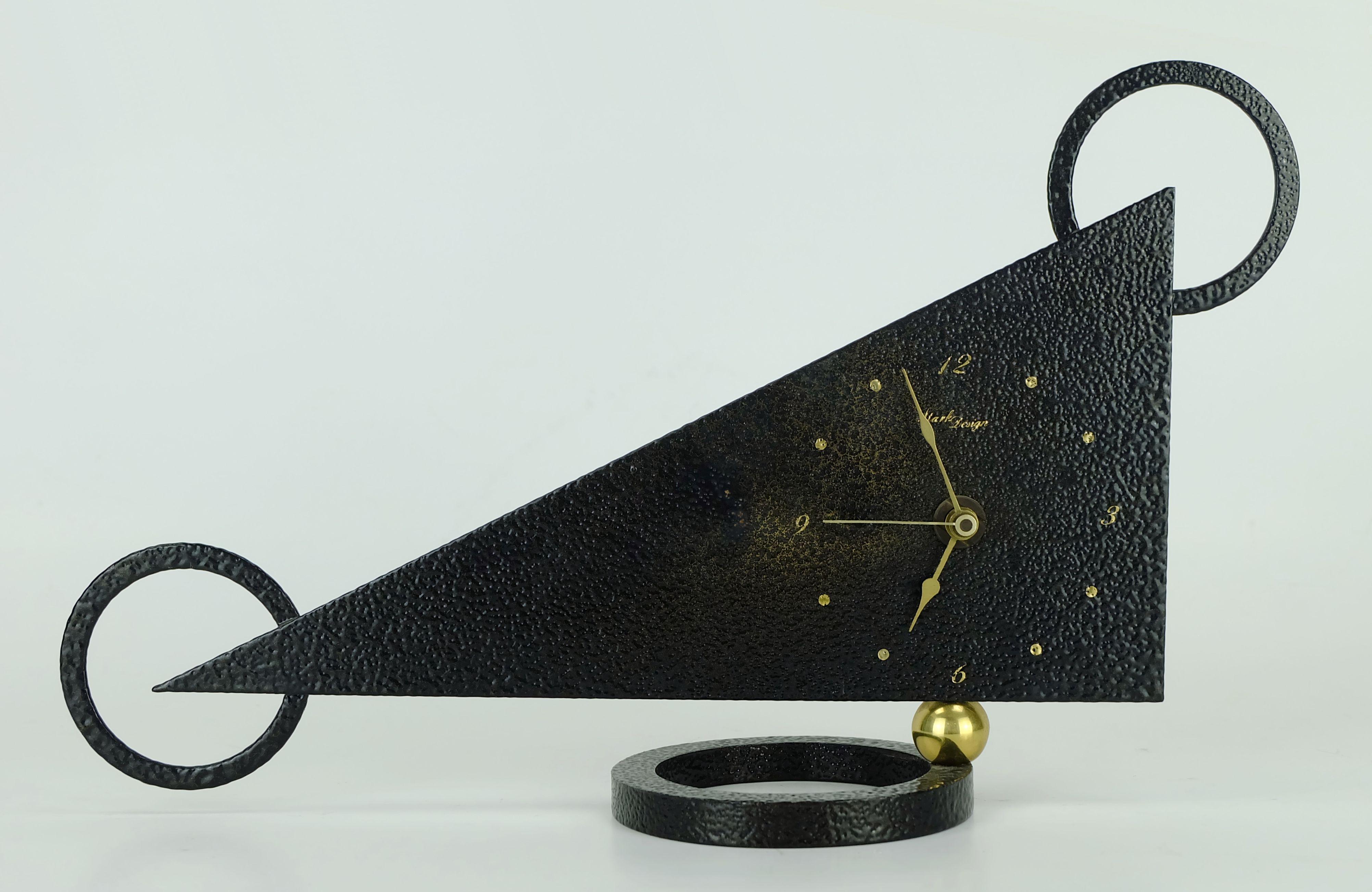 1980s table clock in outstanding design. Made of black lacquered metal, the stand and the body are connected with a brass ball. Brass clock hands. Manufactured by Stark Design, battery works by Junghans (battery is not included).

Dimensions: Width