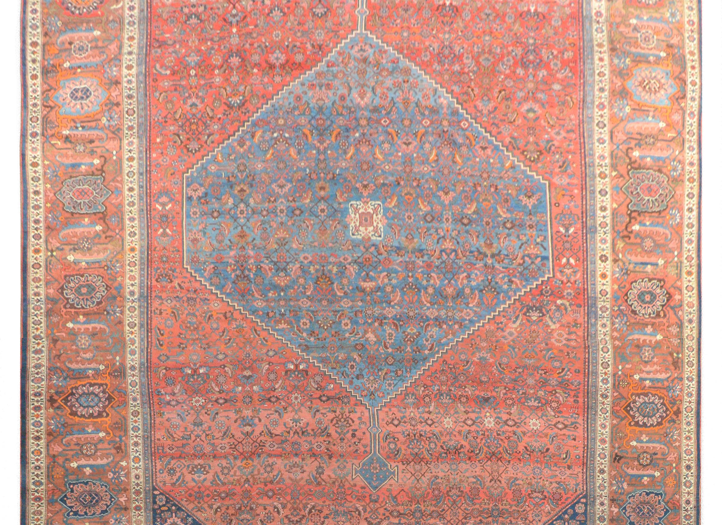 An outstanding palatial-size 19th century Persian Bidjar rug with a large central diamond medallion with a floral and leaf pattern, woven in indigo, orange, cream, brown, and coral, all on an indigo background. The medallion lies on a field of