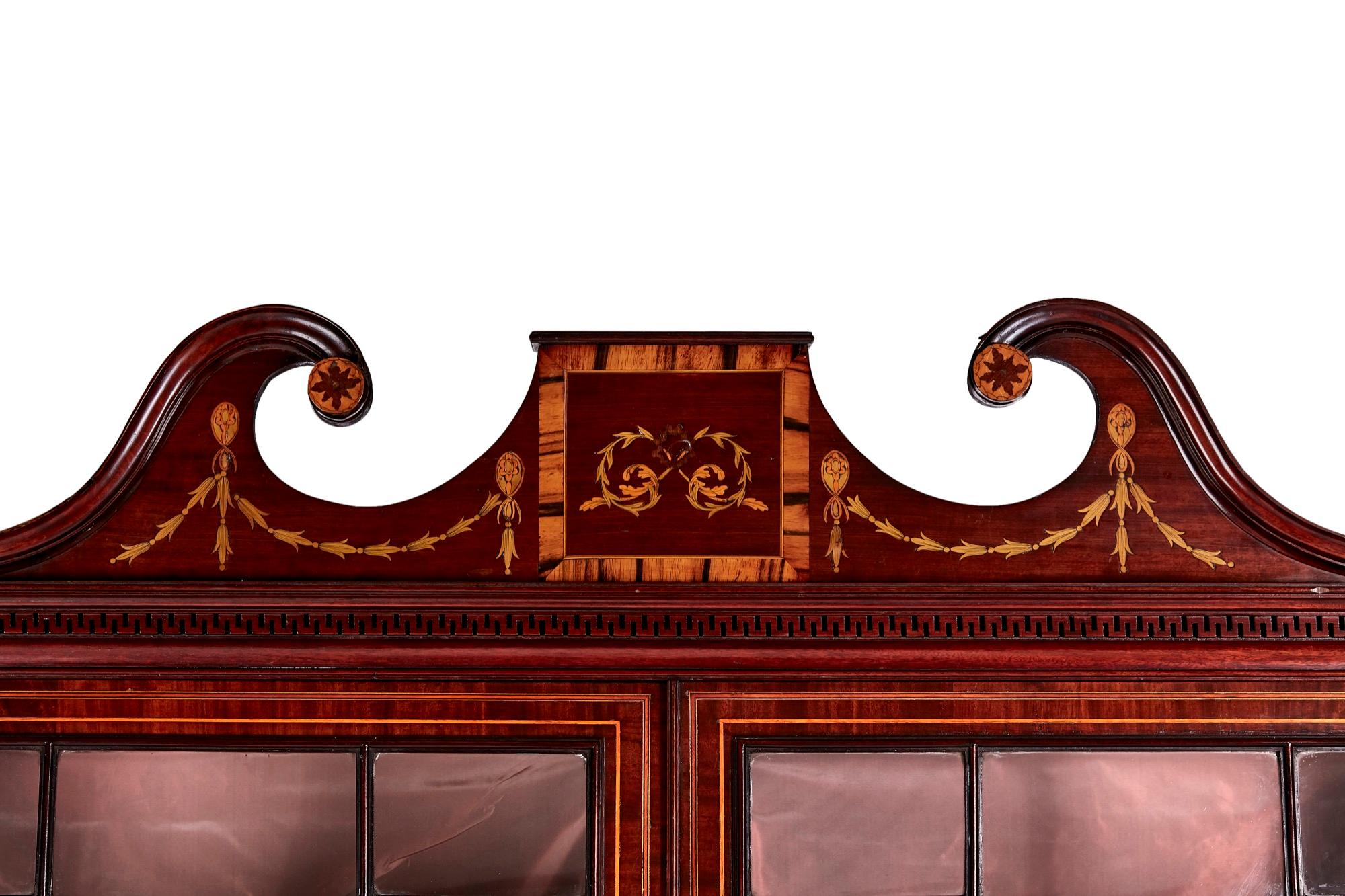 Outstanding antique mahogany inlaid bookcase having a fantastic inlaid swan neck pediment, 2 astragal glazed doors, fitted interior with 3 adjustable shelves. The base having 2 drawers with original brass handles 2 mahogany panelled doors with