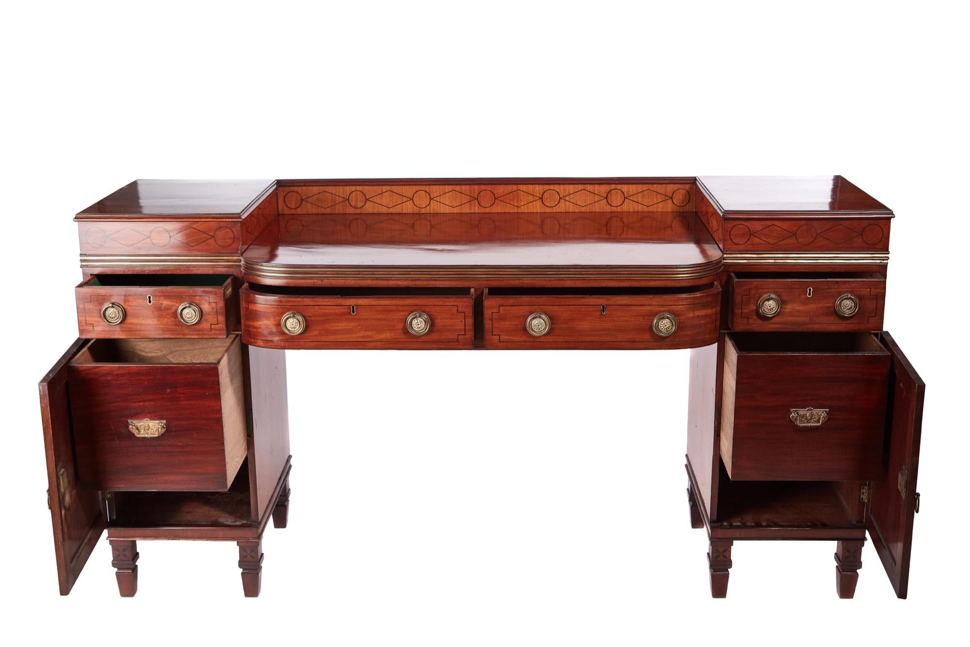 This is an outstanding Regency antique mahogany brass inlaid sideboard with a quality mahogany top, two shaped centre drawers with brass inlay and a inlaid satinwood back, two lovely pedestals inlaid with brass and satinwood to the frieze, two