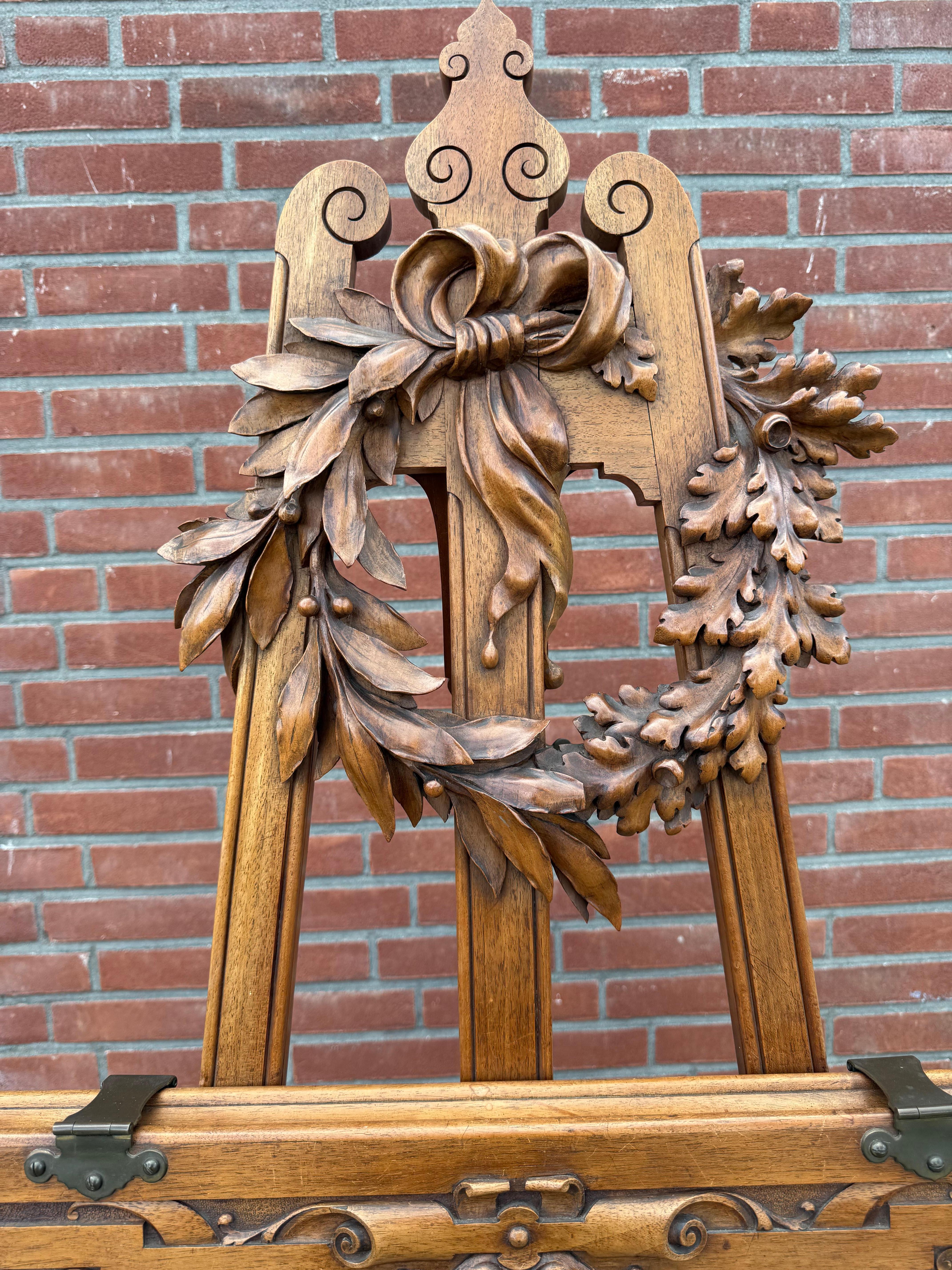 Magnifique stand de dessin ou de peinture en excellent état avec couronne sculptée à la main. 

De temps en temps, un morceau vient vous arrêter dans votre élan. Ce chevalet ancien est l'une de ces trouvailles. Sculpté à la main dans un riche noyer
