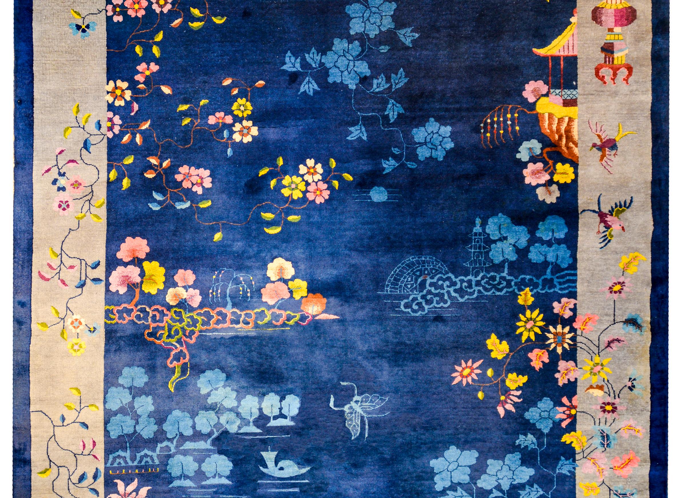 An outstanding early 20th century Chinese Art Deco rug with a rich dark indigo field with lighter indigo and multicolored blossoming peonies. The border is beautiful, with a wide inner gray stripe, and a thin dark indigo outer stripe, both overlaid