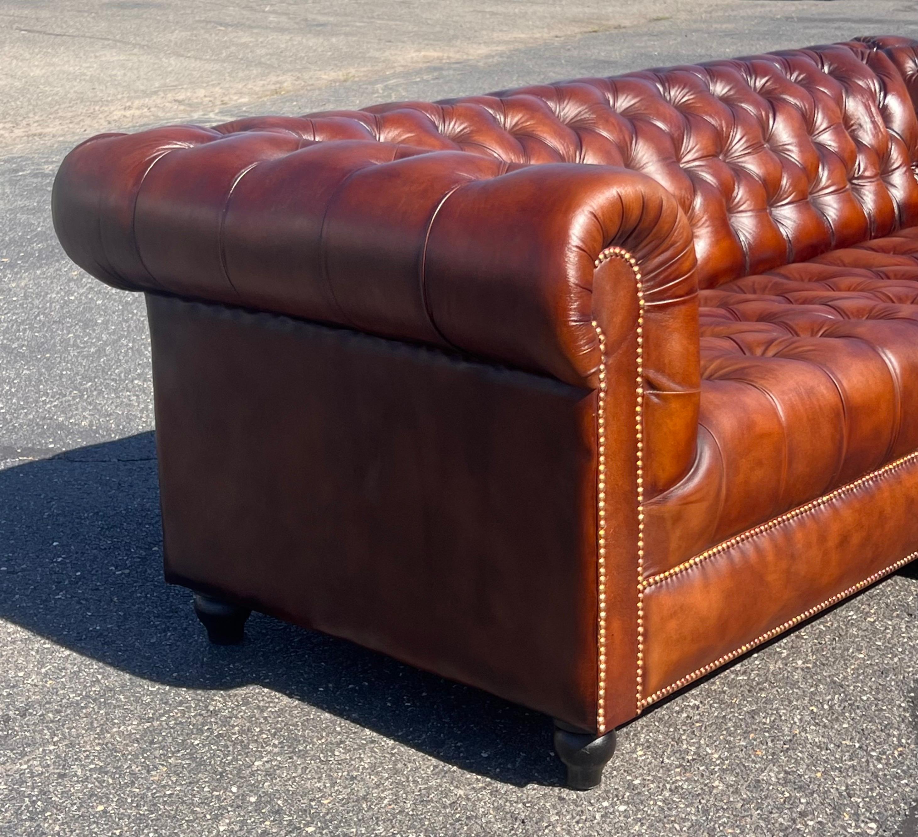 This stunning English-made Chesterfield tufted bench sofa exudes sophistication and timeless appeal. Upholstered in a rich tobacco brown whiskey-colored leather, the sofa features a fully tufted back and seat, paired with a firm, supportive bench