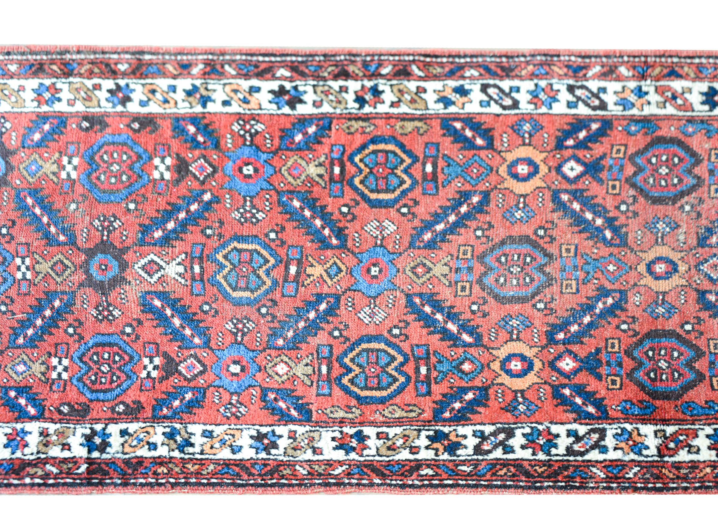 An outstanding early 20th century Karabagh rug with a beautiful trellis pattern with myriad stylized flowers and leaves woven light and dark indigo, white, and cream set against a wonderful pale crimson background and surrounded by a border with