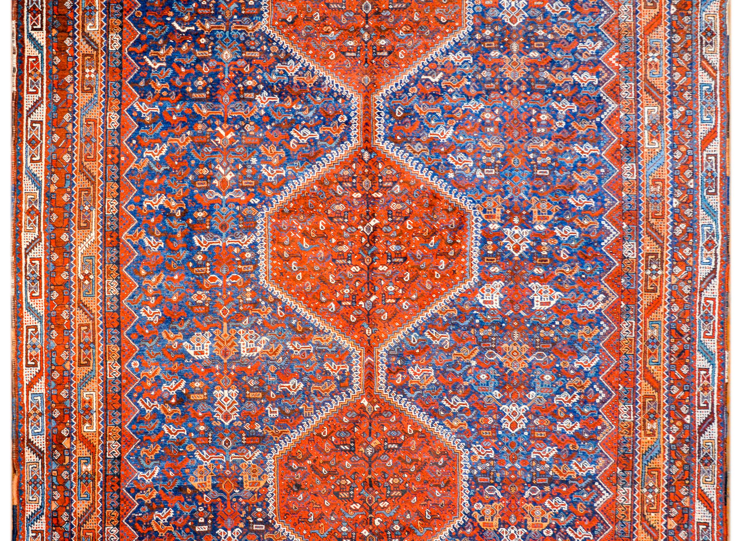 An outstanding early 20th century Persian Khamseh rug with hundreds of multi-colored chickens woven in crimson, white, and gold, on a gorgeous indigo background. The border is extraordinary with multiple thin geometric patterned stripes, woven in