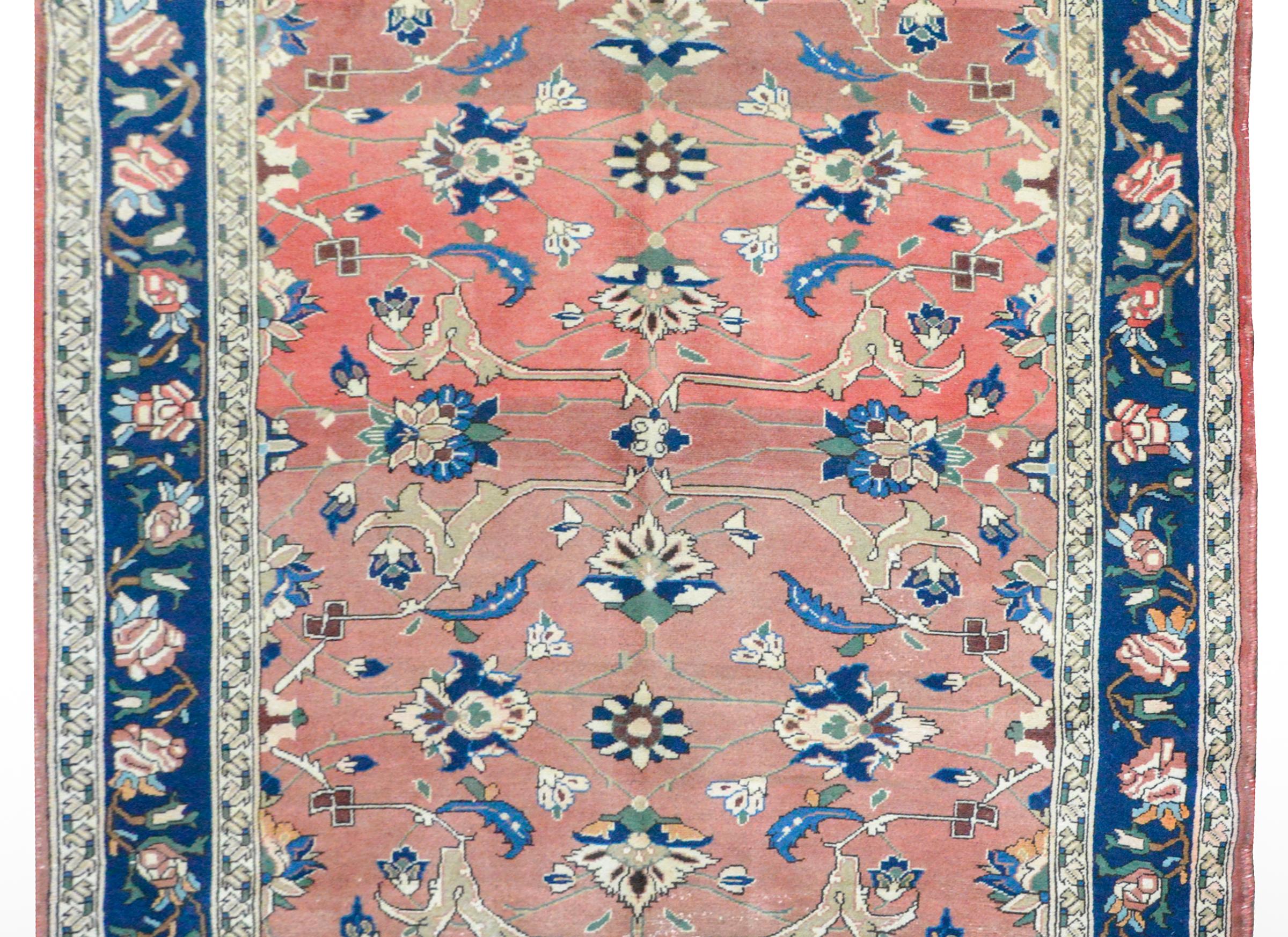 An outstanding early 20th century Persian Lilihan rug with a finely rendered floral pattern woven in light and dark indigo, cream, white, and green wool, again a beautiful abrash coral background. The border is wide with a scrolling vine and floral