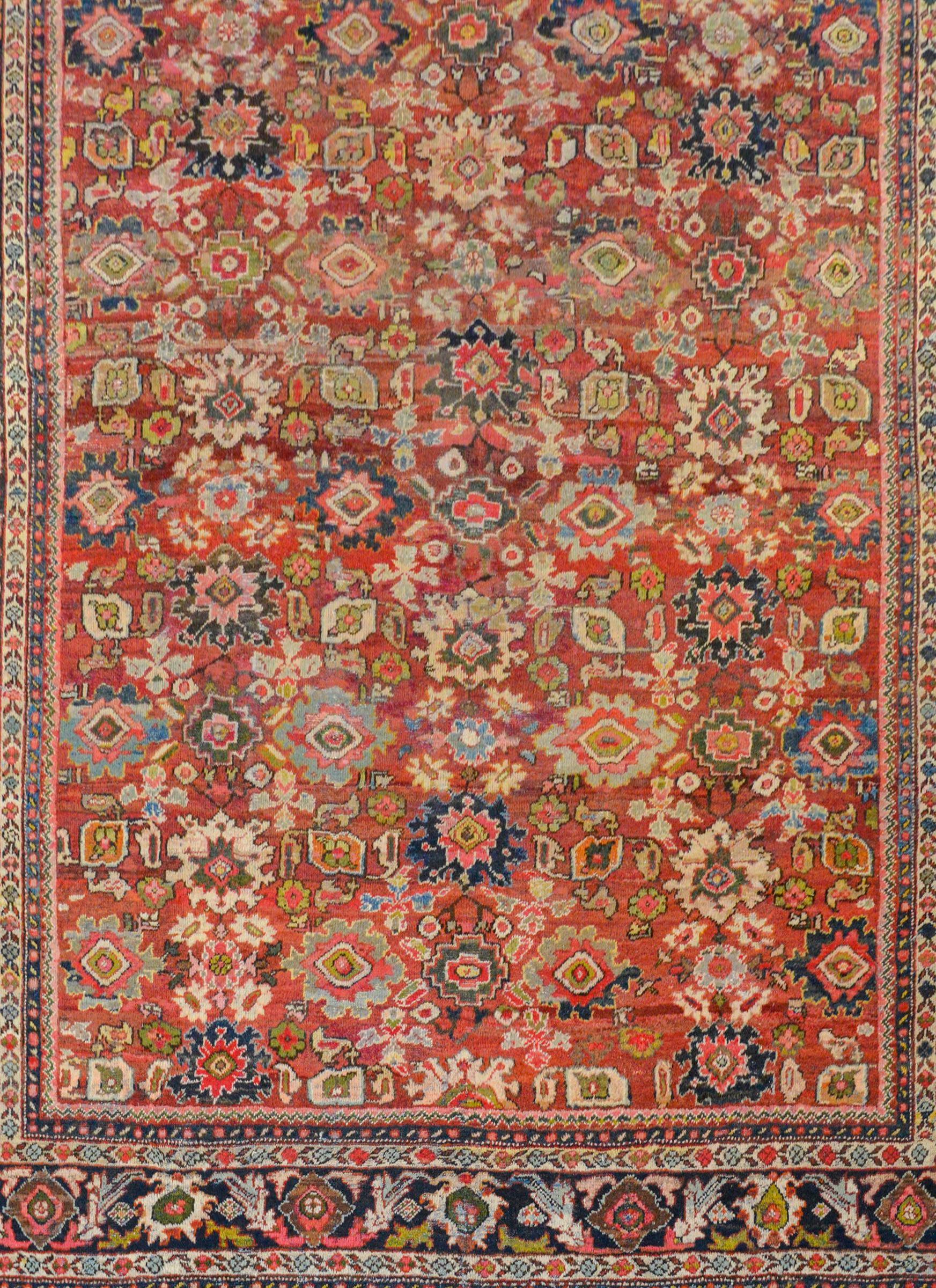 An outstanding early 20th century Persian Mahal rug with an incredible all-over pattern of myriad flowers and leaves woven in light and dark indigo, gold, green, crimson, white, and cream colored wool on an incredible abrash crimson background. The