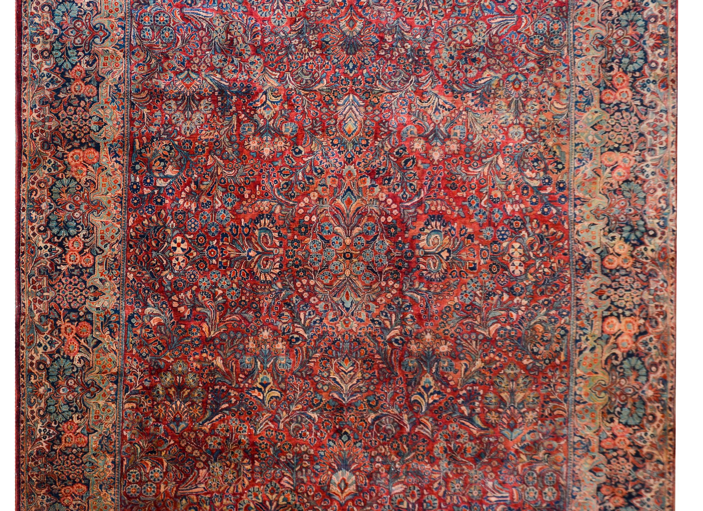 Excepcional alfombra Sarouk de principios del siglo XX con un tradicional motivo floral espejado en toda la superficie, tejida en ricos colores índigos, arándanos y crema, y rodeada por uno de los mejores bordes florales asociados que hemos visto en