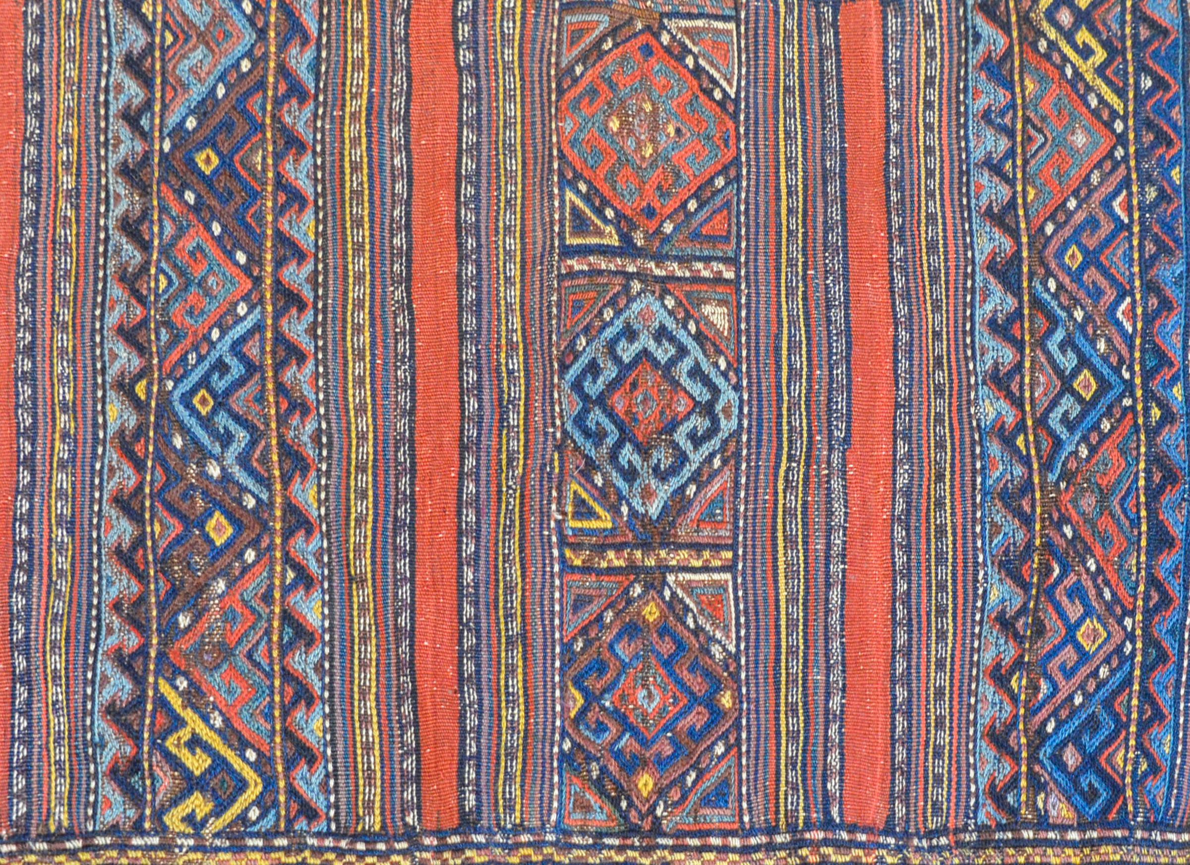 An outstanding early 20th century shahsevan bag face rug with an elaborately woven pattern containing solid stripes, geometric patterned stripes, all woven in indigo, gold, crimson, and white vegetable dyed wool. The border is similarly patterned,