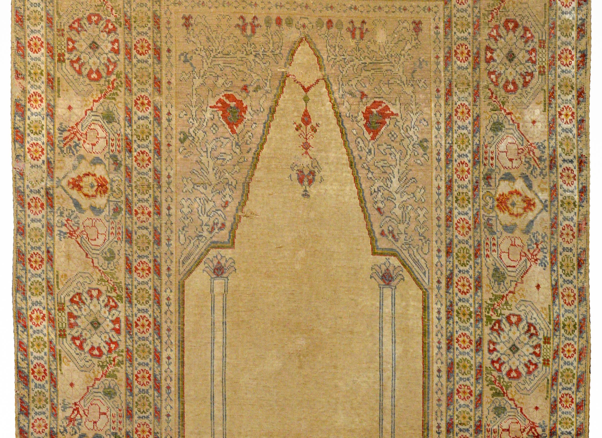 An outstanding early 20th century Turkish handwoven silk prayer rug with a beautiful pattern of large-scale flowers, scrolling vines and leaves, woven in coral, pale blue, green, and gold, all on a champagne colored ground.