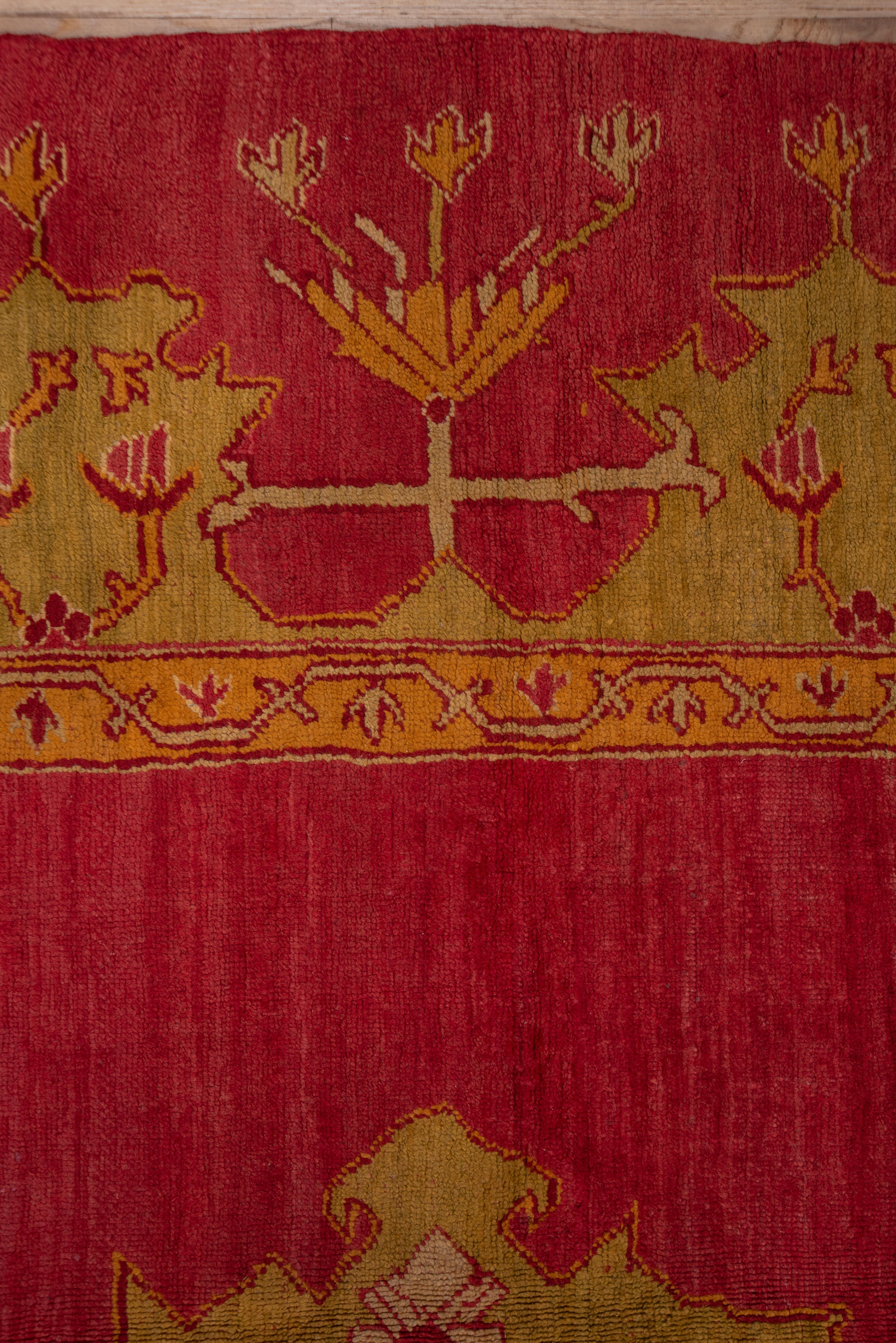 This is an outstanding Oushak in excellent pile, with a brisk Turkey red open field showcasing a jagged lime and gold pendanted medallion with tonally matching double corners. The very wide border has an elaborate reciprocal crenelation pattern in