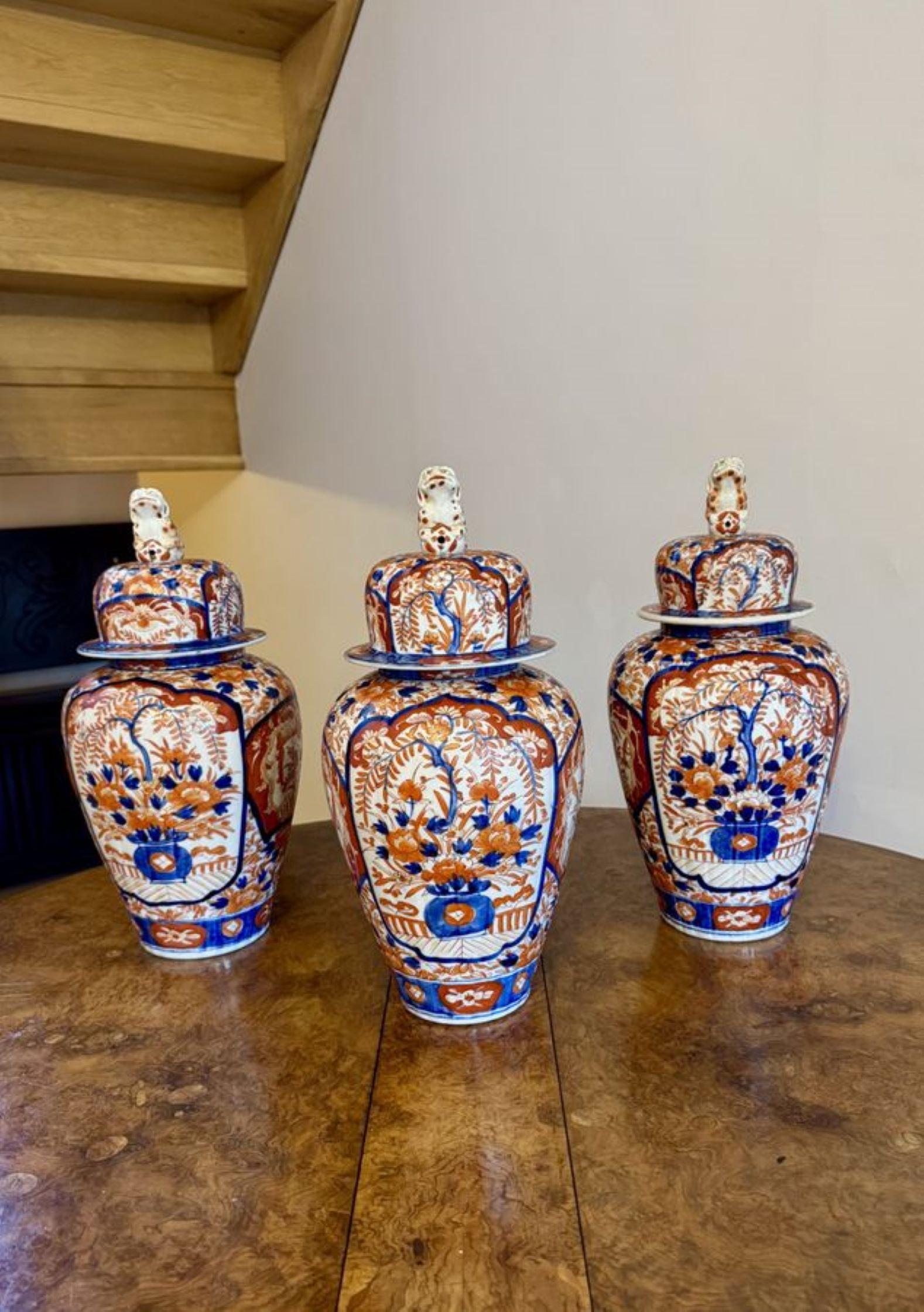 Exceptionnelle garniture de qualité fantastique de trois vases imari japonais anciens, ayant une garniture fantastique de trois grands vases imari japonais anciens à balustre et couvercles décorés de paniers de fleurs dans des panneaux de feuilles,