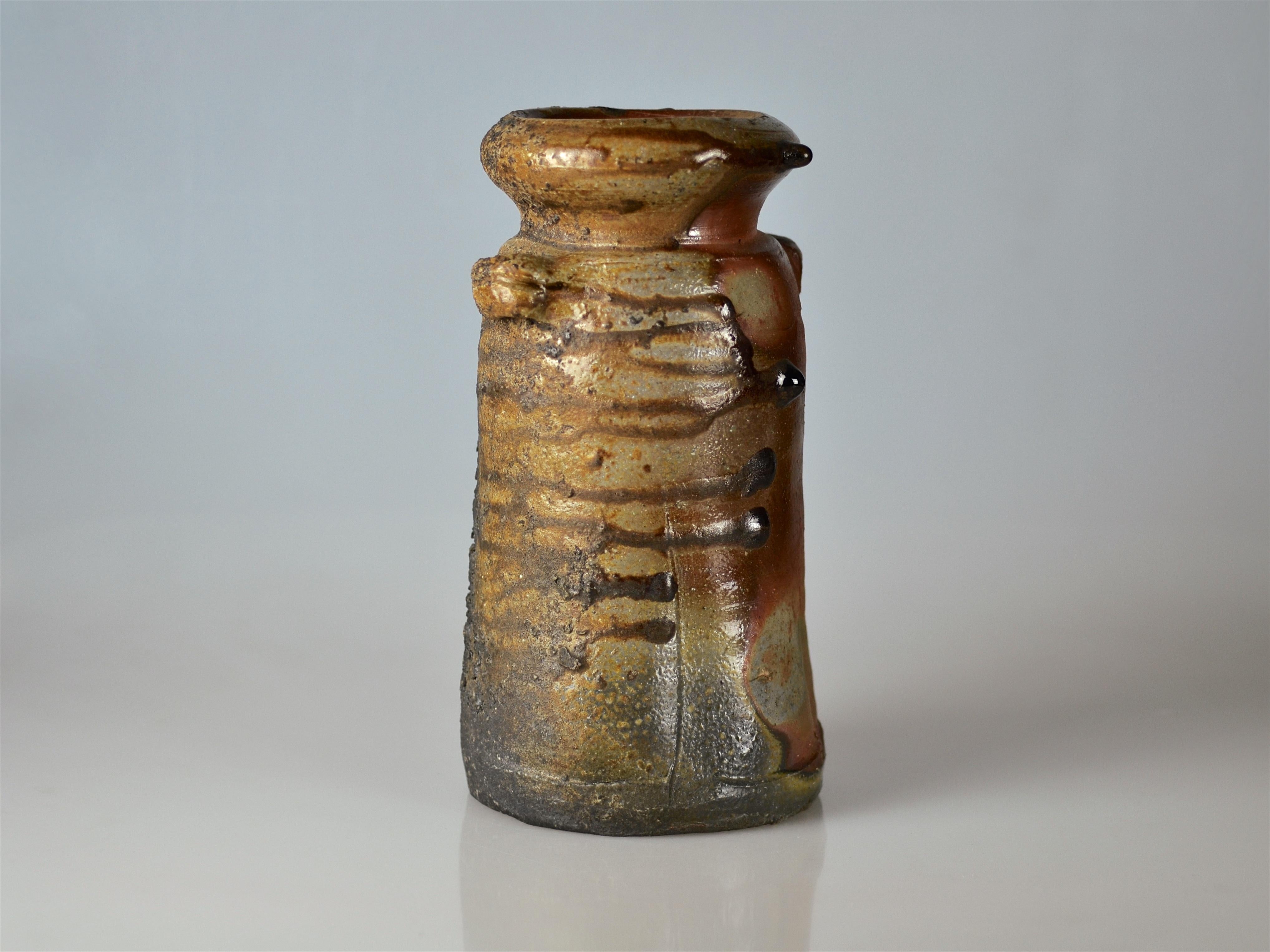 An excellent traditional ash gazed Bizen flower vase made by Isezaki Mitsuru (1934-2011). The piece was laying on the side during firing and the results is heavy ash glazing in strong horizontal glaze traces, which are often ending in single,