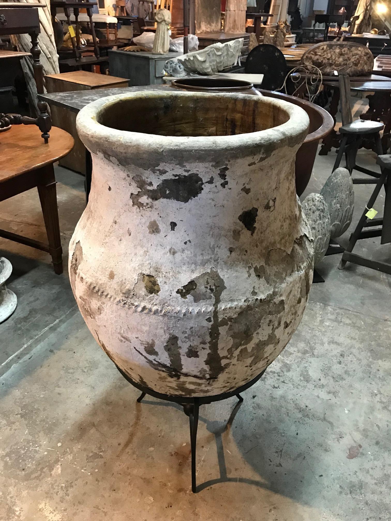 An outstanding white washed terracotta Olive Jar from the Andaluz region of Spain. The jar is presented in its custom made iron stand. Sensational patina. A wonderful accent for any interior or garden.