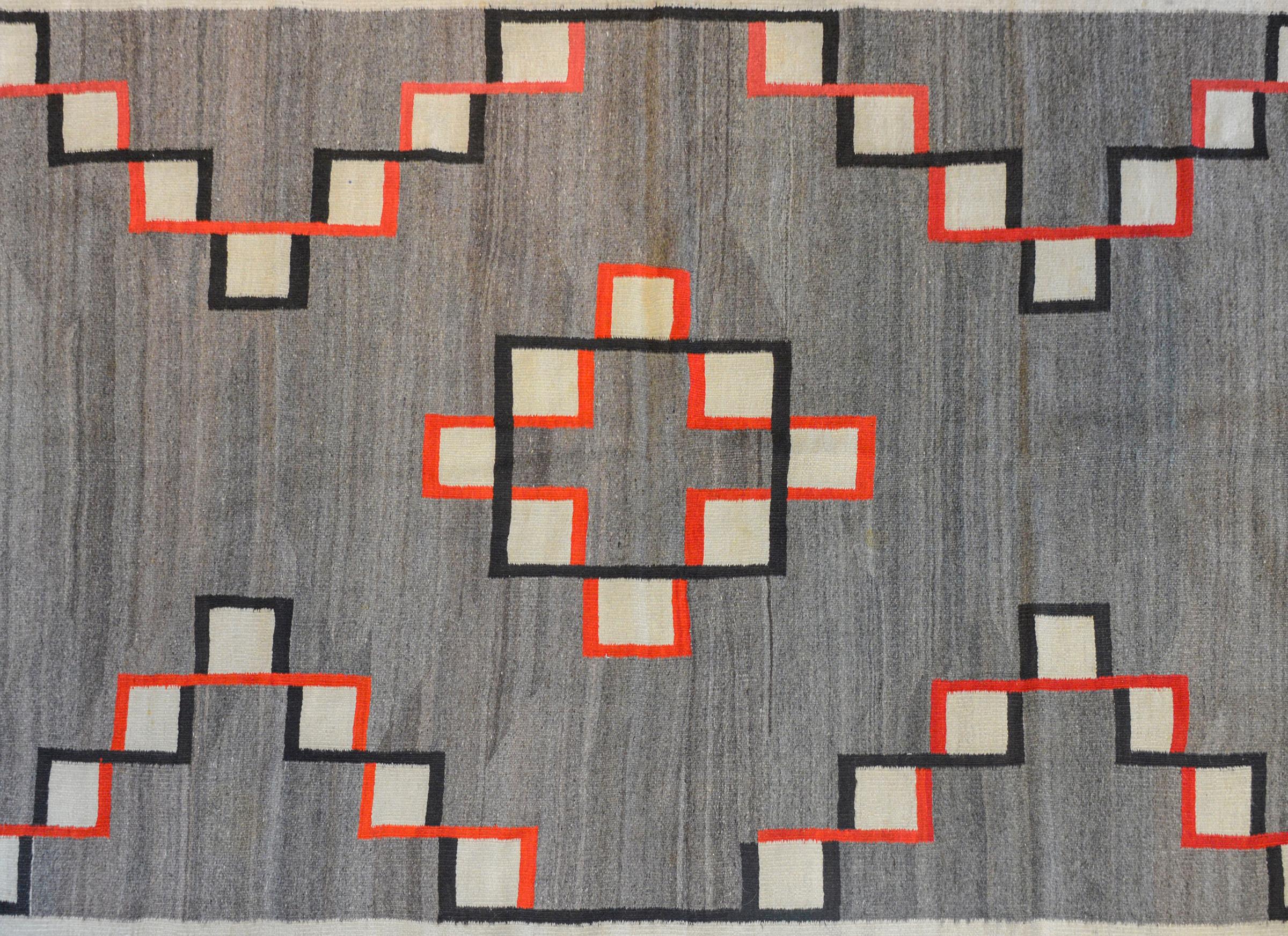 An outstanding late 19th century Navajo rug with a fantastic pattern of interlocking crimson and black lines around white squares creating a zigzag pattern across an abrash gray field.