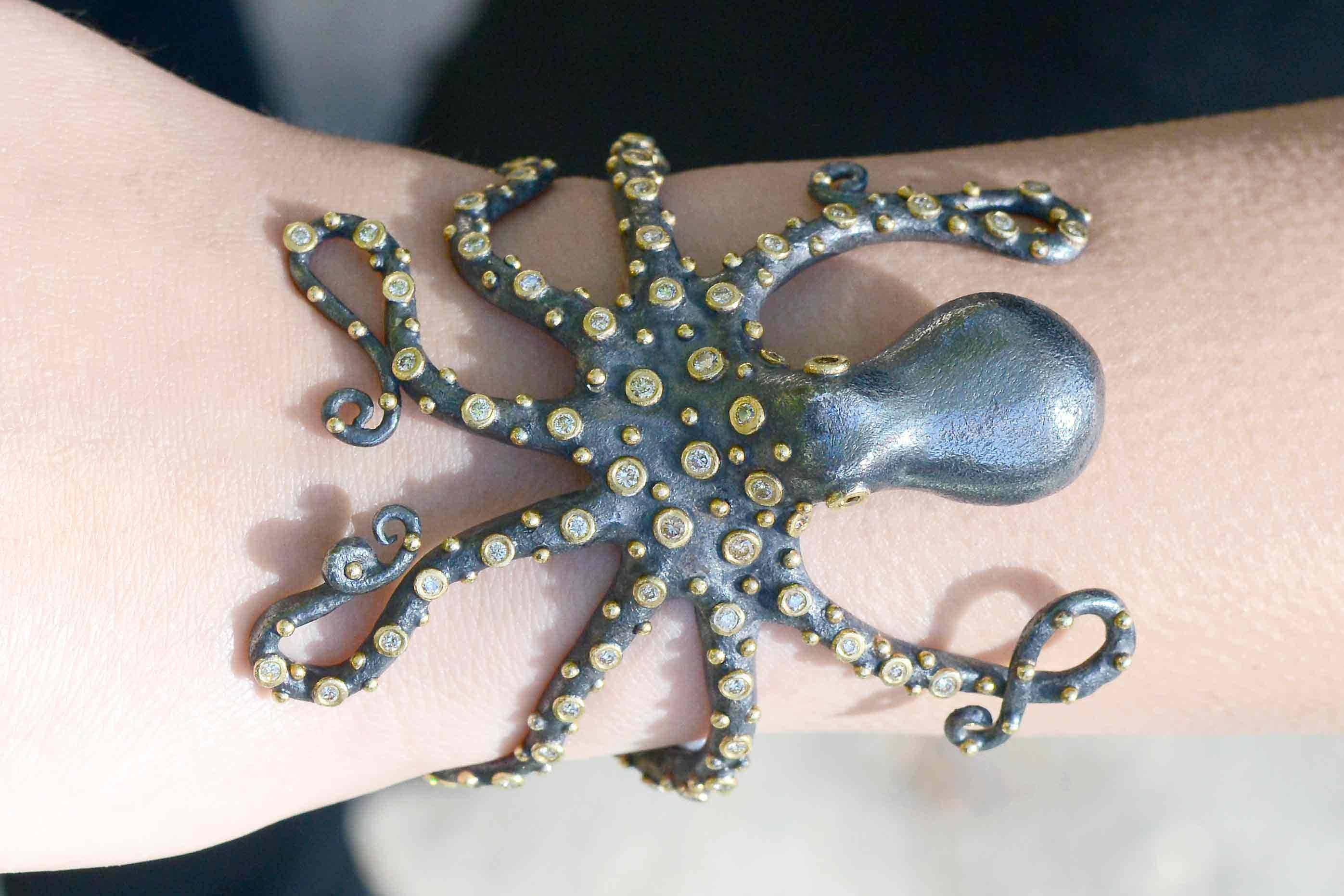 An outstanding octopus cuff bracelet is artfully rendered in rich 24 karat gold and oxidized silver 2 tone. Wrapping seductively around the wrist, this sea-life creature features diamond studded tentacles and eyes totaling 1 3/4 carats. Made to fit