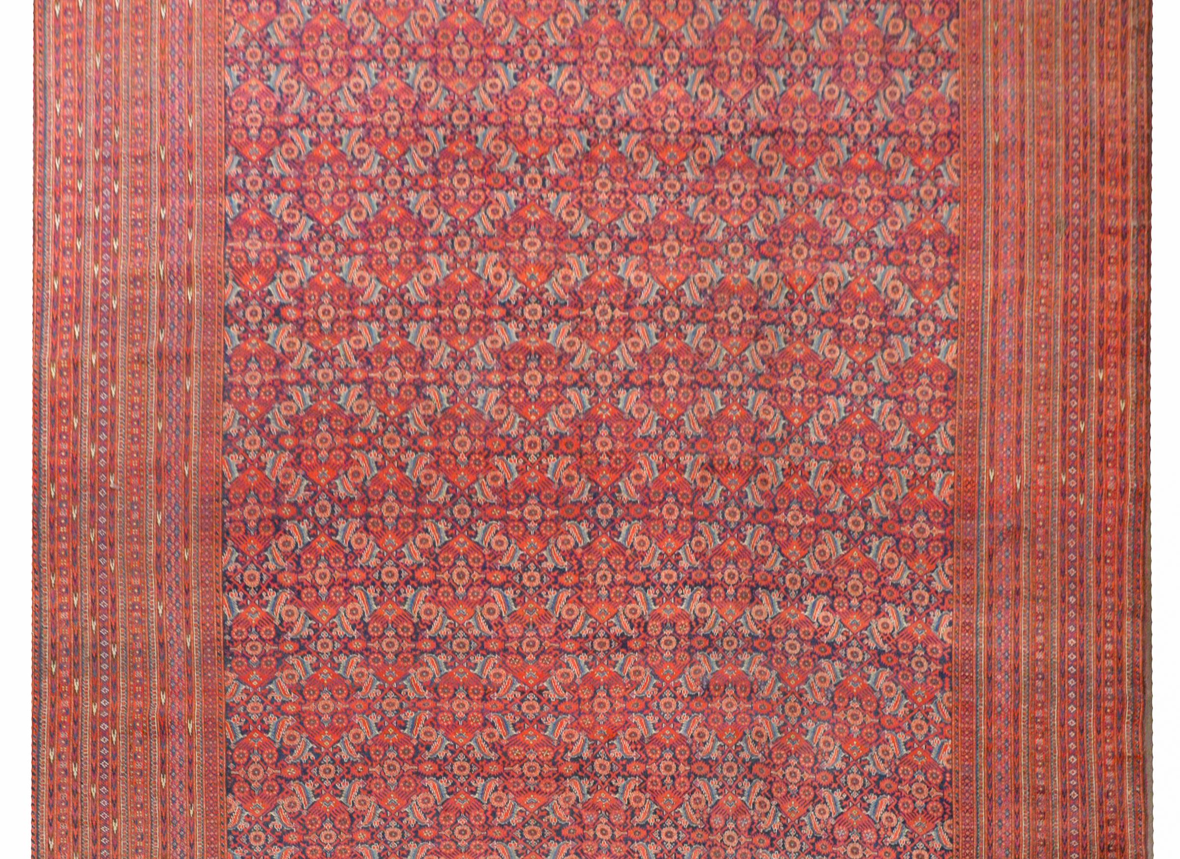 An outstanding early 20th century palatial-size Afghani Bashir rug with a rare and wonderful all-over floral and leaf lattice pattern woven in crimson, light and dark indigo, on a dark indigo background. The border is extraordinary with several
