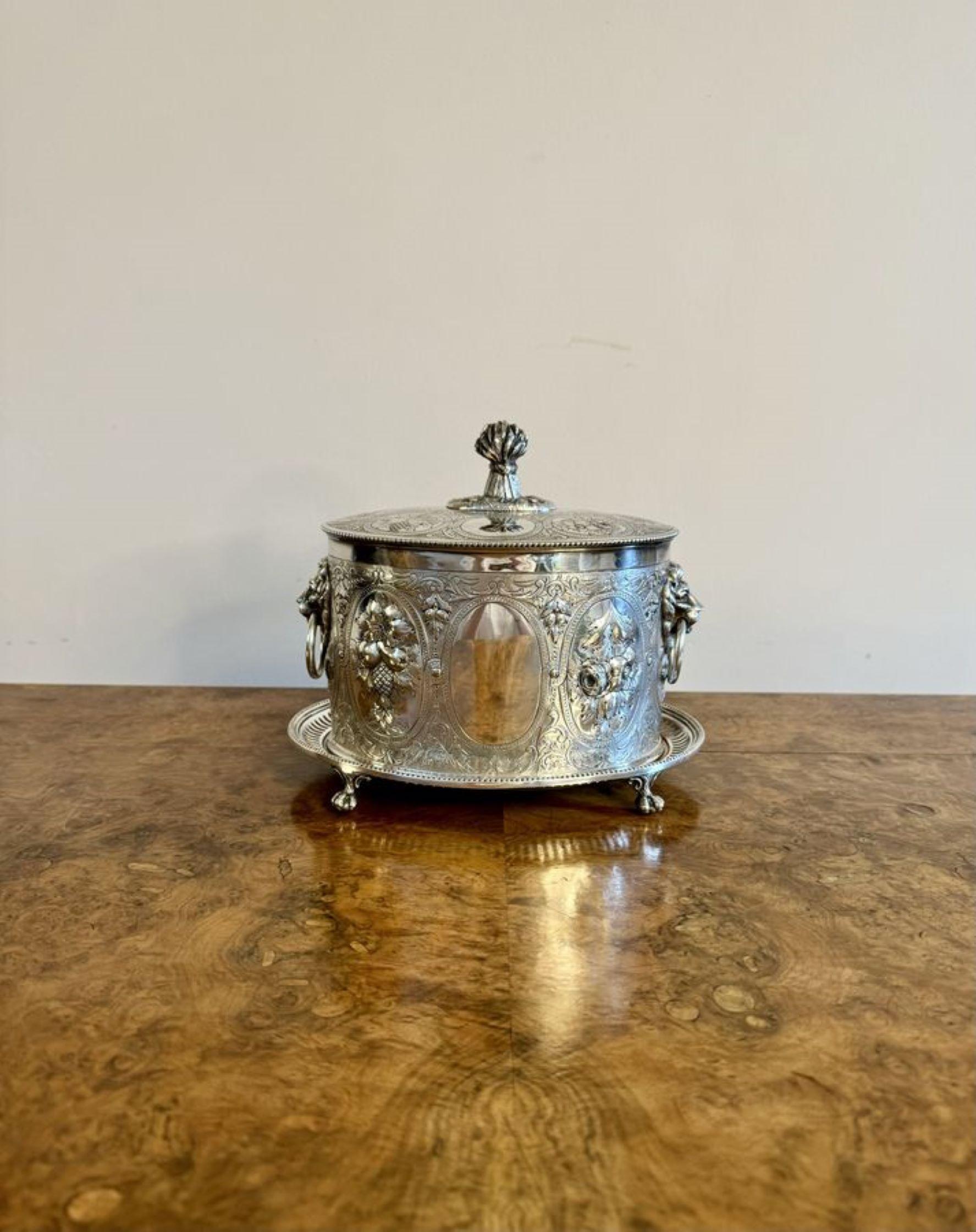 Fantástico barril de galletas bañado en plata de la época eduardiana, decorado con volutas, flores y frutas, con una tapa que se abre para revelar un compartimento, con asas en forma de cabeza de león a los lados, elevado sobre patas de garra y
