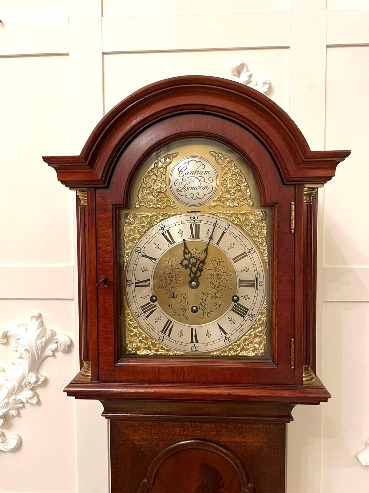 Outstanding quality antique mahogany eight day triple chiming Grandmother clock having an outstanding quality mahogany case with a shaped arched top glazed and mahogany door flanked by turned mahogany columns with brass caps. The door opens to