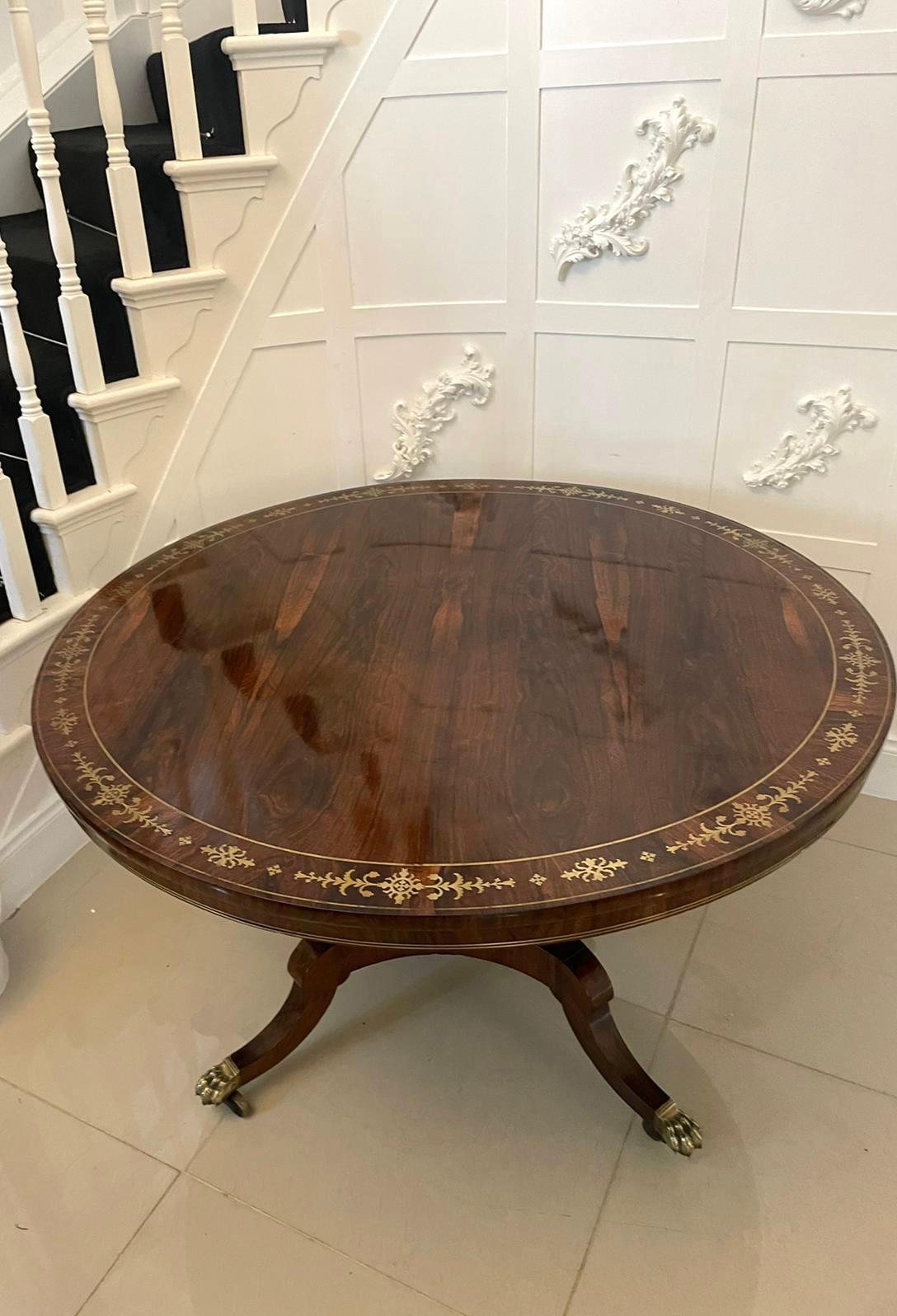 Outstanding quality antique regency brass inlaid rosewood centre/dining table having an outstanding quality circular rosewood brass inlaid tilt top supported by an elegant turned pedestal column raised on a shaped platform base with shaped sabre