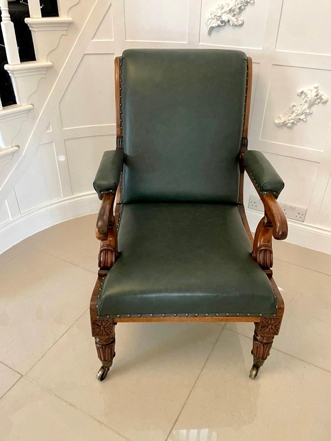 Outstanding quality antique Regency quality rosewood reclining armchair having fabulous carving and newly reupholstered in a quality green leather with close nailed standing on splendid carved tulip legs to the front with original brass cup castors