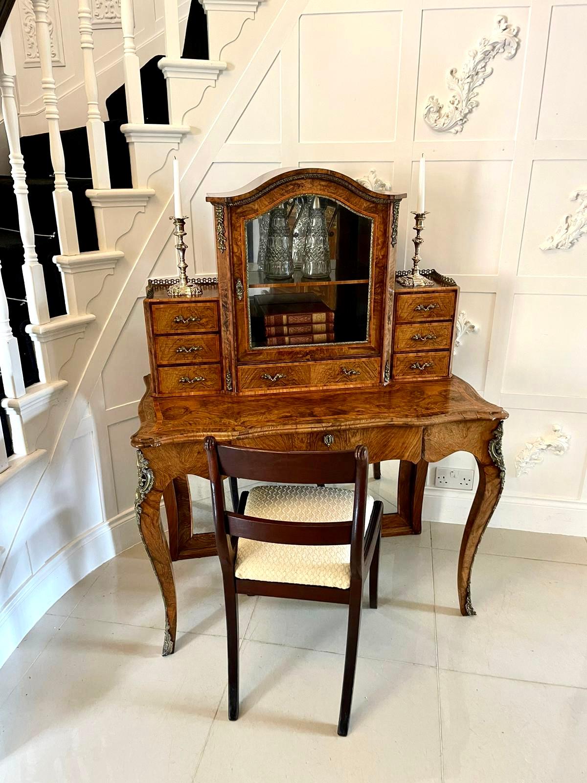 Outstanding quality antique Victorian burr walnut Bonheur de Jour writing desk having a beautifully designed and shaped top glazed cabinet to the centre which opens to reveal a fitted mirror and shelf interior with elegant ormolu mounts to the