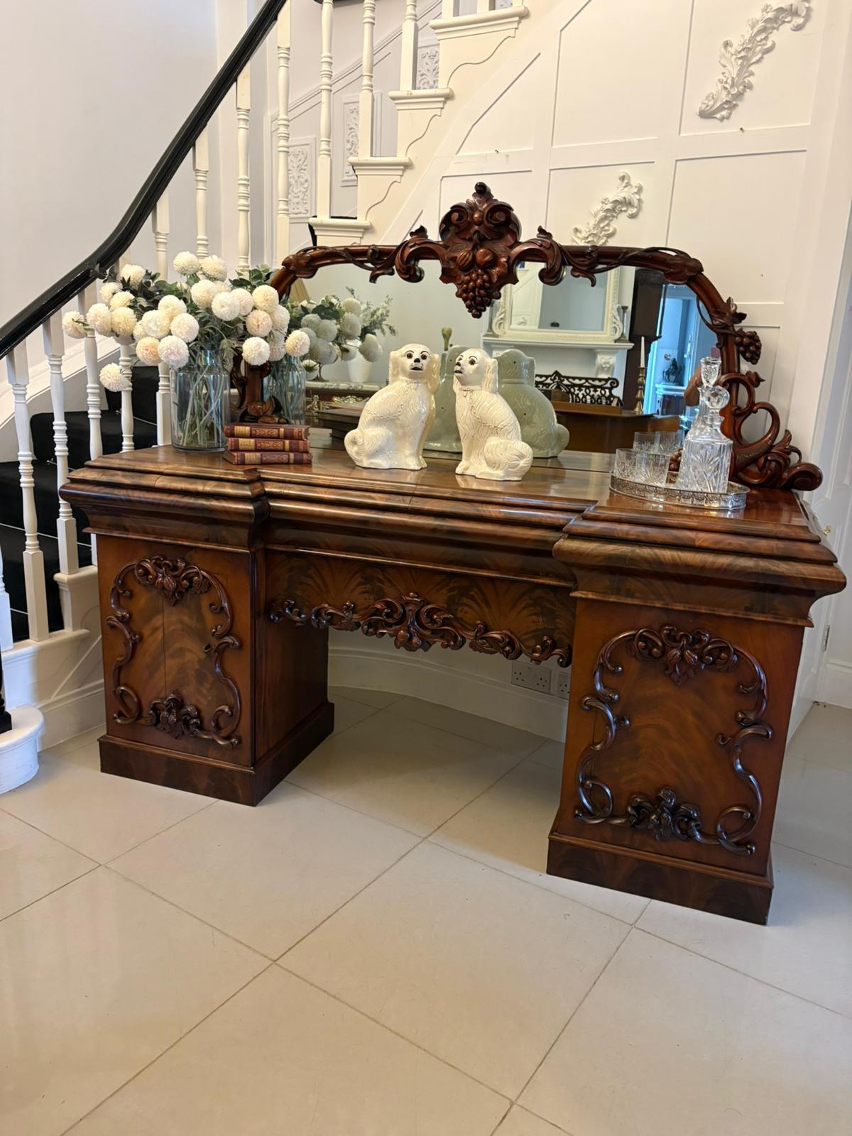 Outstanding quality antique Victorian carved mahogany mirror back sideboard having an outstanding quality carved grape vine and leaf mahogany framed mirror back above a figured mahogany inverted breakfront top, three cushion frieze drawers and