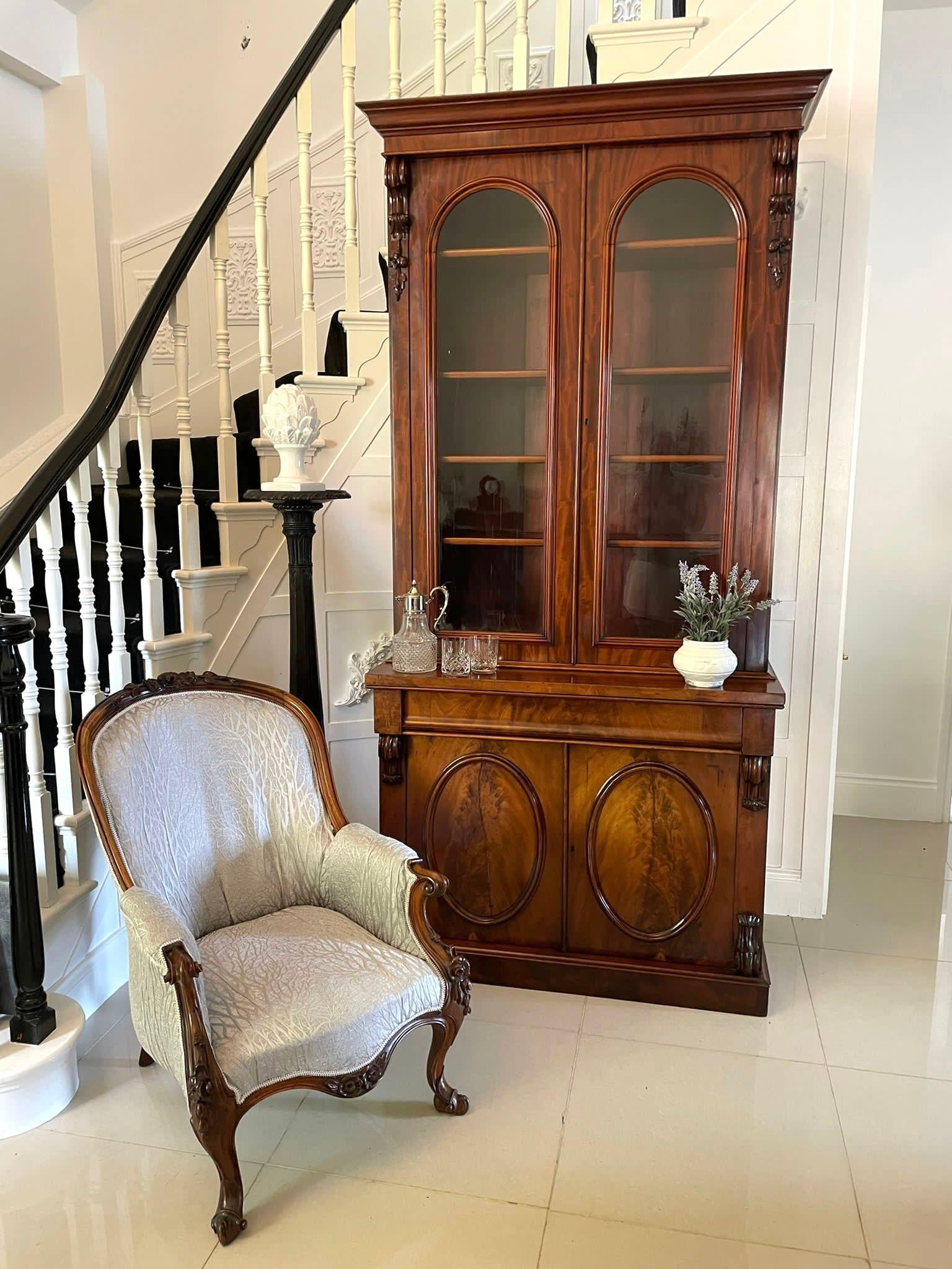 Outstanding quality antique Victorian figured mahogany glazed cupboard bookcase having a shaped moulded cornice above a figured mahogany frieze above a pair of figured mahogany glazed arched shaped doors with mahogany moulding. The doors open to
