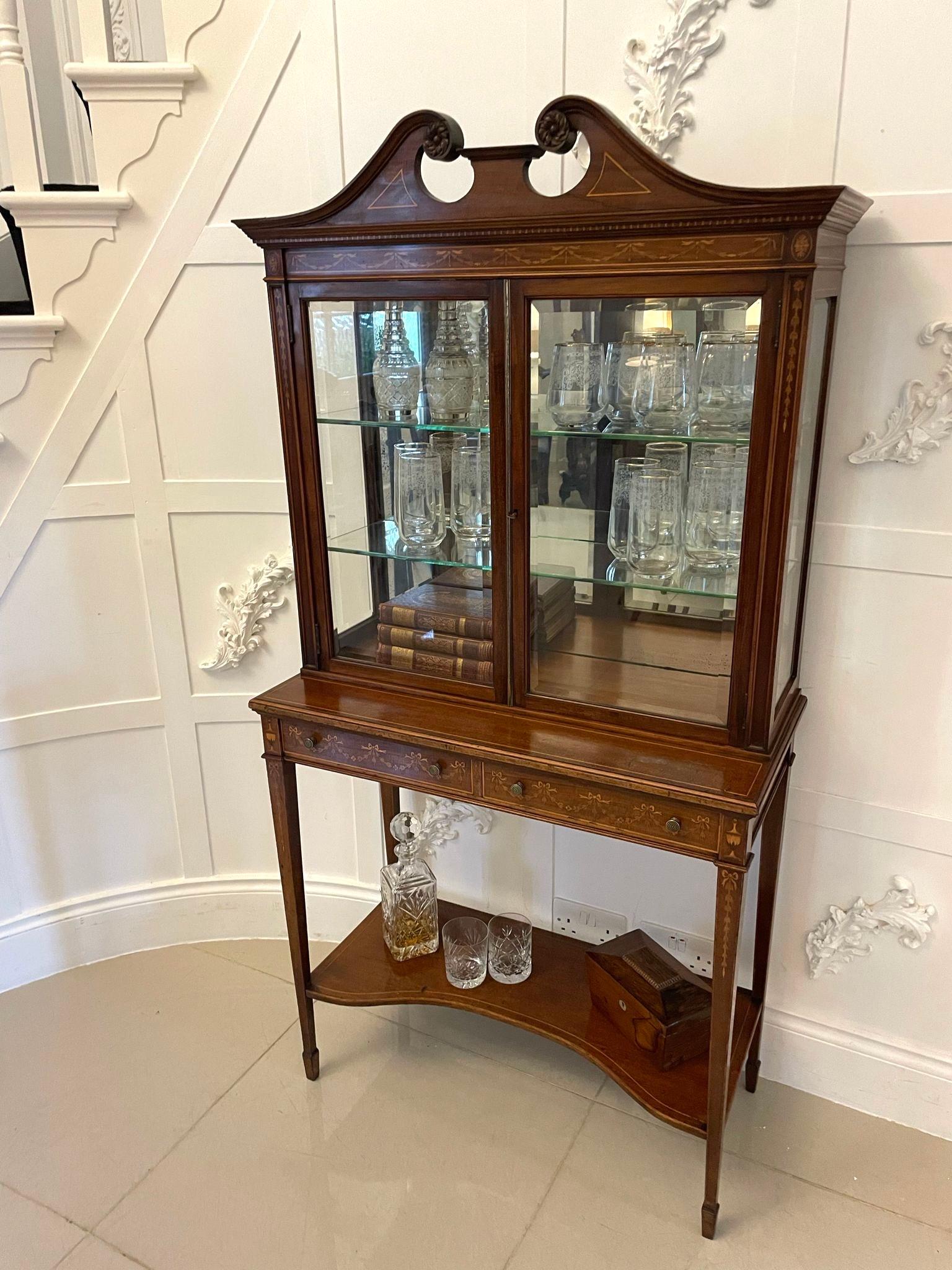 Outstanding quality antique Victorian mahogany inlaid display cabinet having a quality carved and inlaid swan neck pediment above a mahogany frieze inlaid with pretty swags, bows and ribbons above a pair of bevelled edge glazed doors opening to