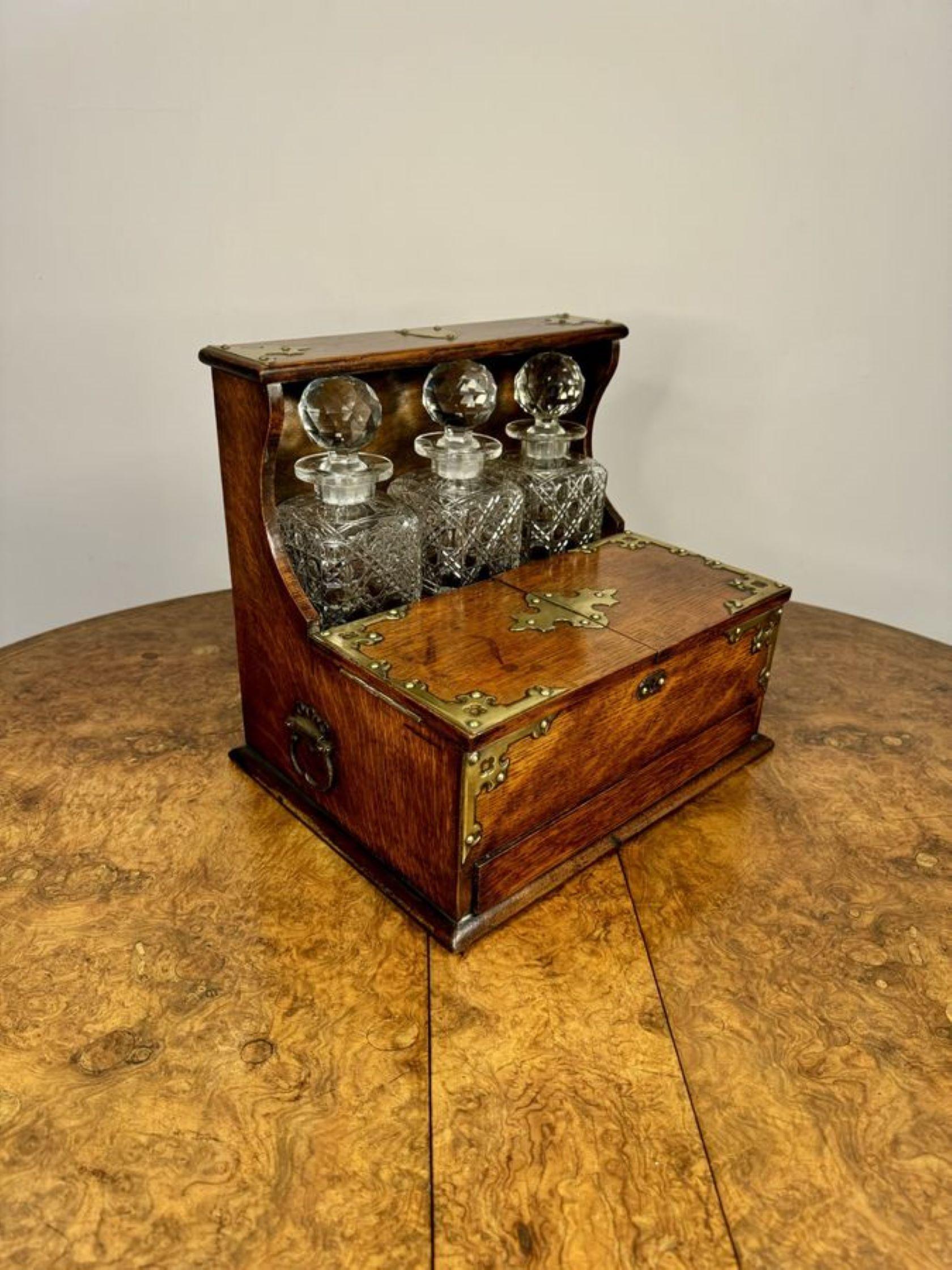 Quality antique Victorian oak tantalus and games box, having a quality oak tantalus with quality brass mounts and carrying handles to the sides, having a compartment with three square cut glass decanters above a compartment with fitted sections