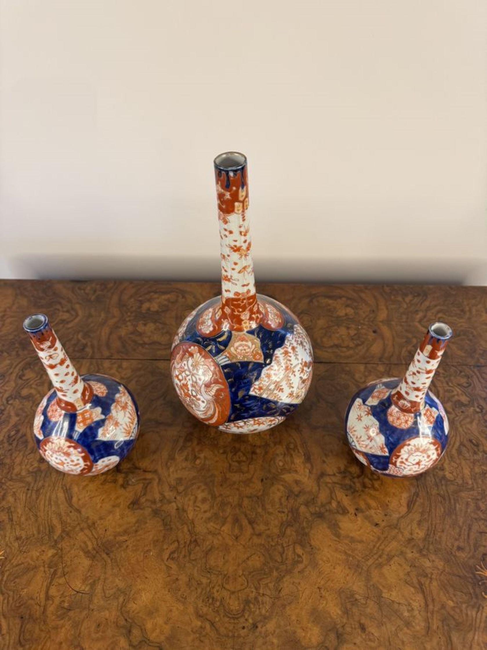 Eccezionale guarnizione di tre antichi vasi giapponesi a forma di imari, composta da un vaso grande e due vasi più piccoli, con corpi a forma di bulbo sotto un collo sottile, decorati con ventagli, uccelli, insetti, volute e dipinti a mano in