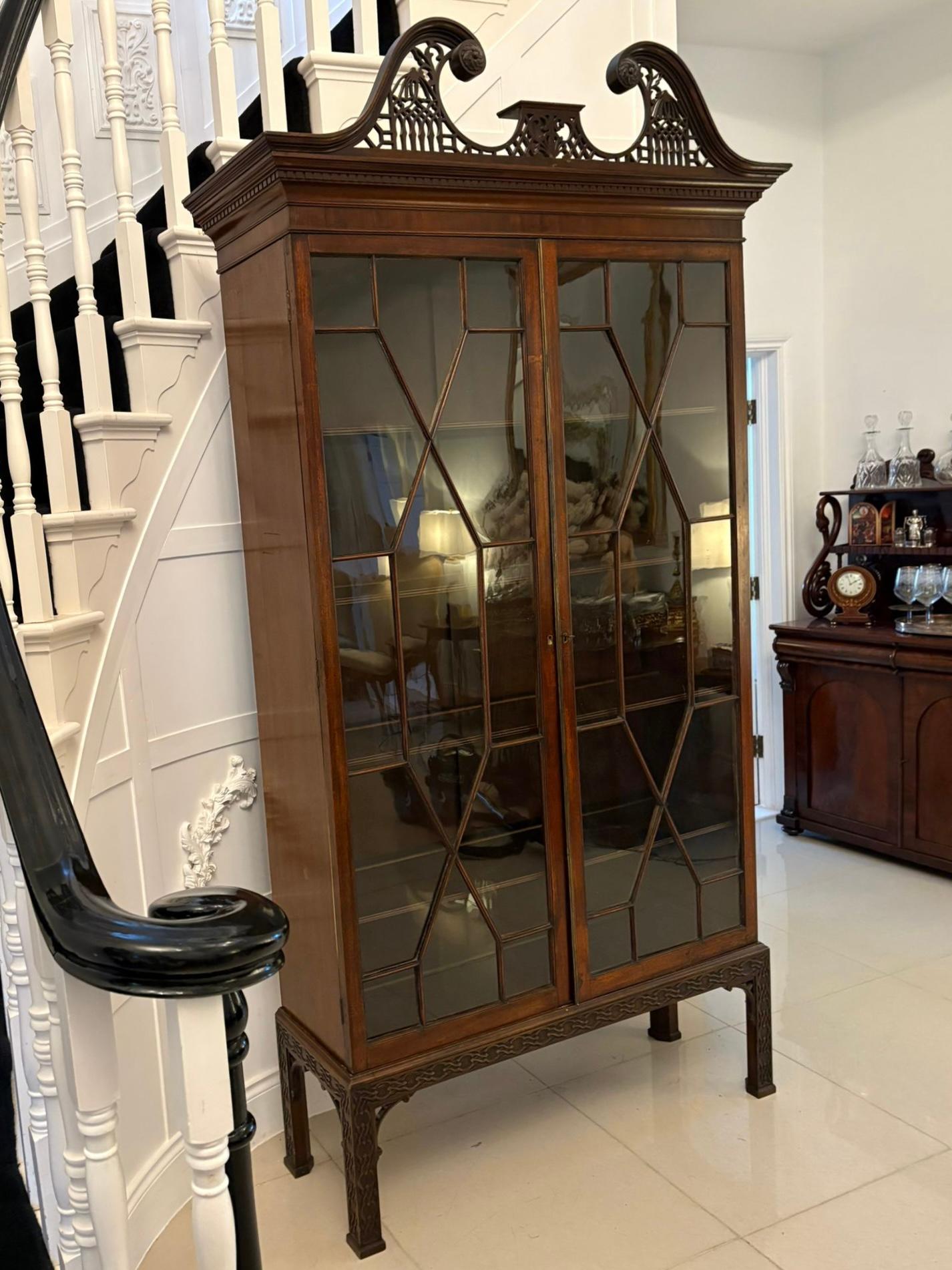 Grande libreria antica di qualità in mogano intagliato con vetri astrali che presenta una magnifica cornice a collo di cigno intagliata di qualità sopra una coppia di porte con vetri astrali che si aprono per rivelare quattro ripiani in mogano con