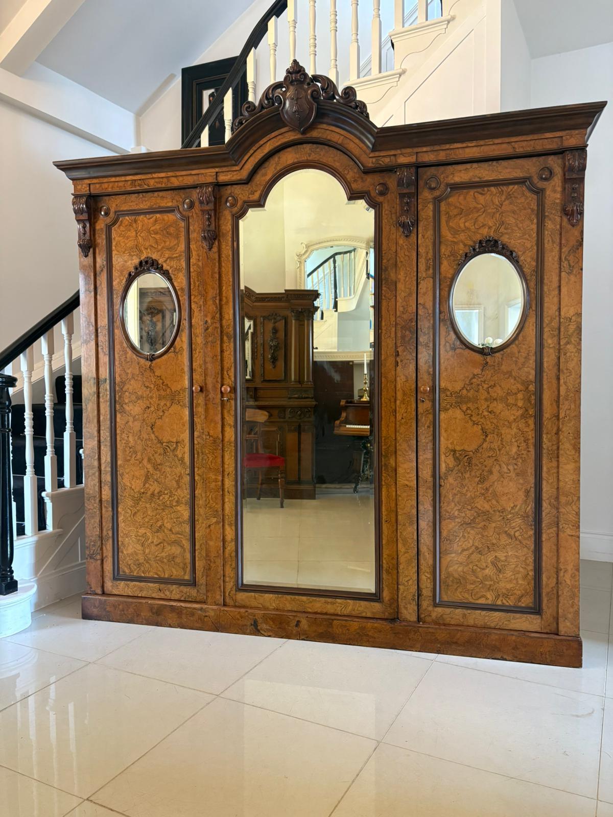 Outstanding quality large antique Victorian unusual carved burr walnut 3 door wardrobe having a magnificent  quality carved walnut shaped cornice above a large burr walnut bevelled edge mirror door opening to reveal a fitted interior consisting of 3