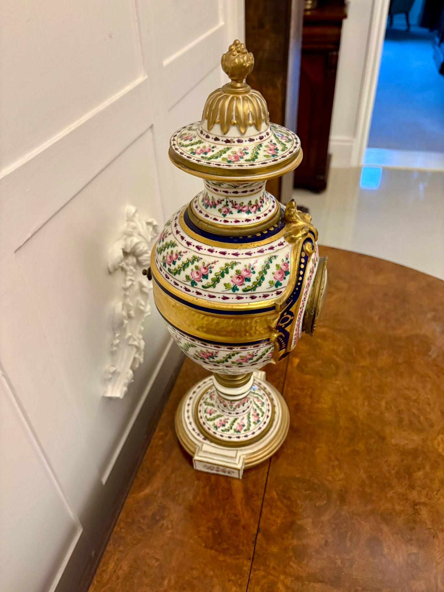 Magnifique horloge de manteau en porcelaine peinte à la main en forme d'urne. Le boîtier est en porcelaine peinte à la main en forme d'urne avec un décor de fleurs et de feuilles dans de merveilleuses couleurs bleu, rose, vert, blanc et or. Elle est