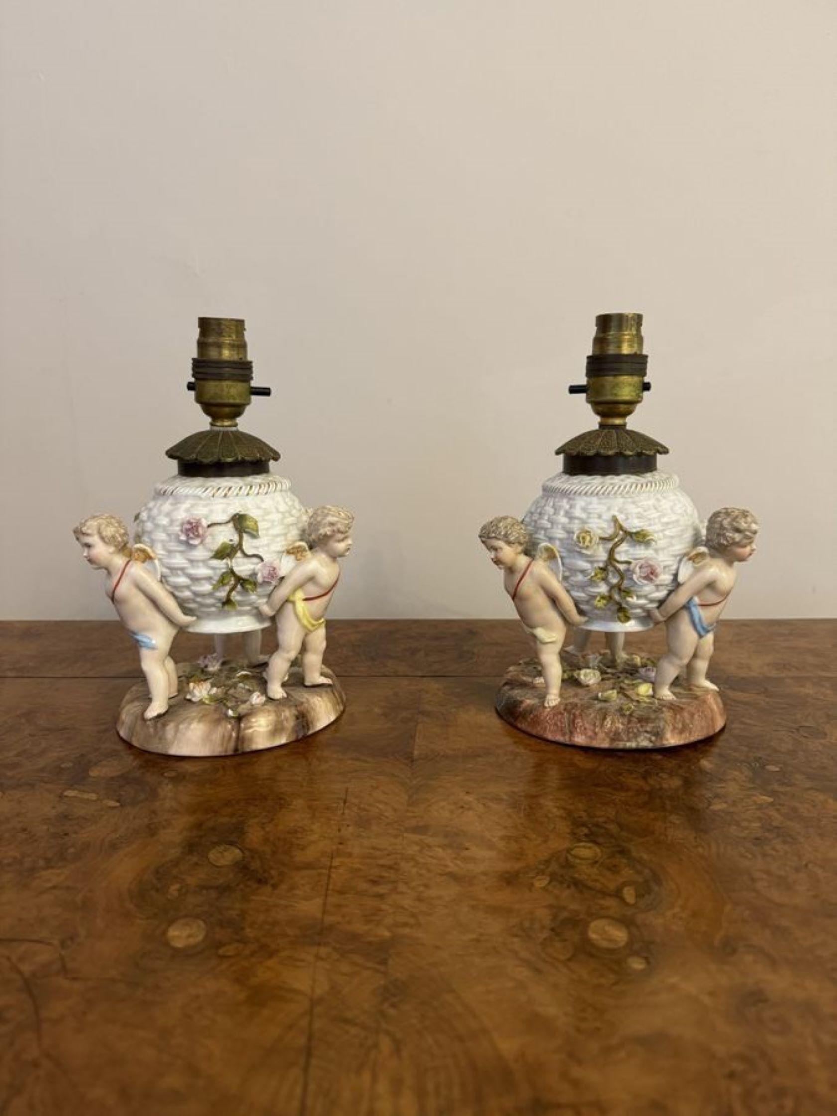 Paire exceptionnelle de lampes anciennes en porcelaine de Sitzendorf, comprenant trois chérubins en porcelaine entourant un centre de forme circulaire décoré de belles fleurs et de feuilles dans de superbes couleurs vertes, roses, jaunes et orange,