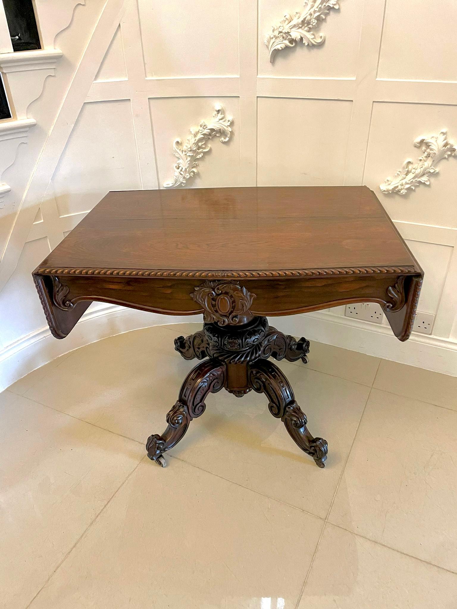 Outstanding quality Victorian carved rosewood sofa table having a fabulous carved gadrooned edge detail to the top with two drop leaves. The frieze is fitted with one long carved drawer supported by a fantastic carved solid rosewood column; it