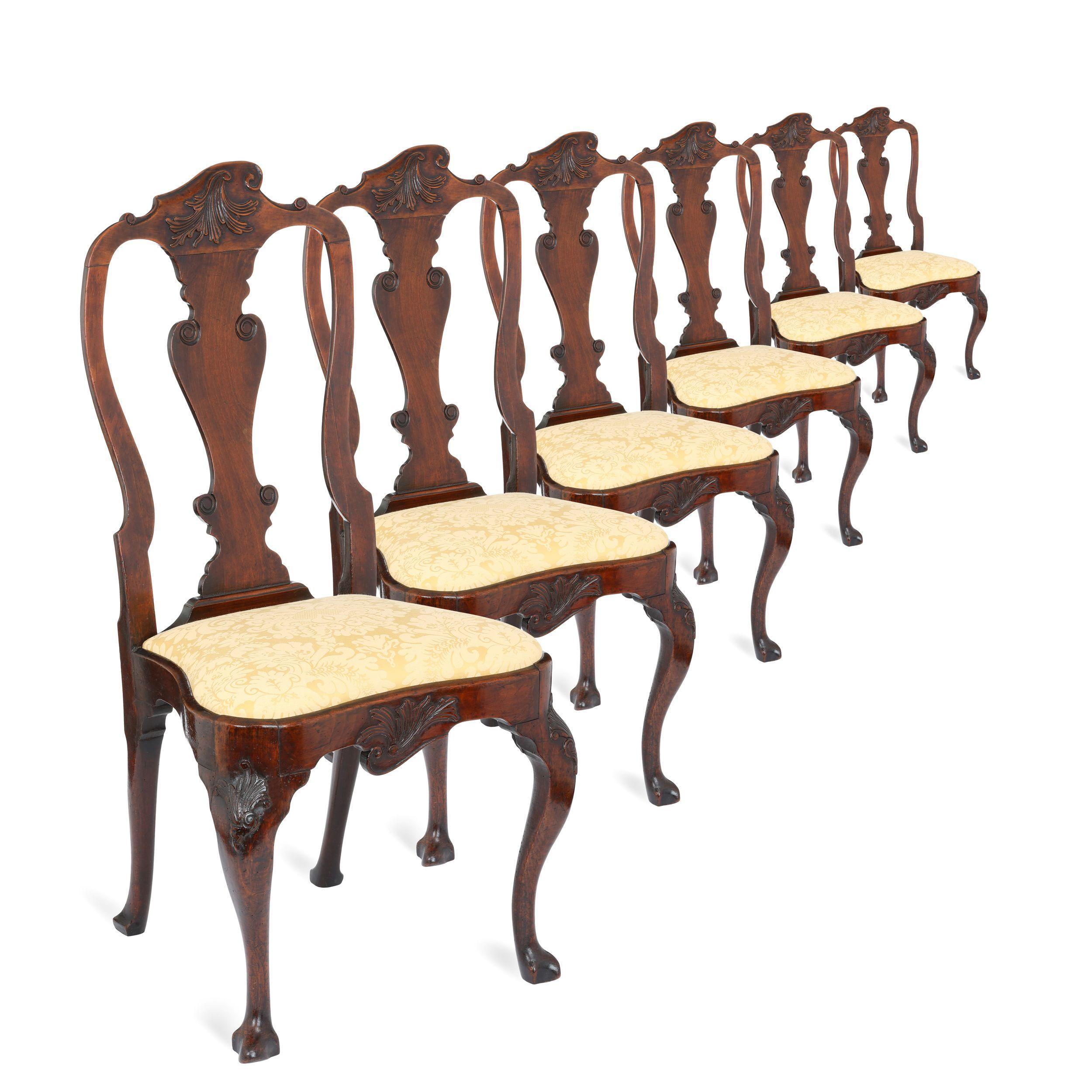 Un ensemble extrêmement rare de six chaises de salle à manger George II en noyer massif sur des pieds cabriole sculptés et d'un design extrêmement rare. Les dossiers présentent des motifs asymétriques sculptés de volutes au sommet des dossiers, qui