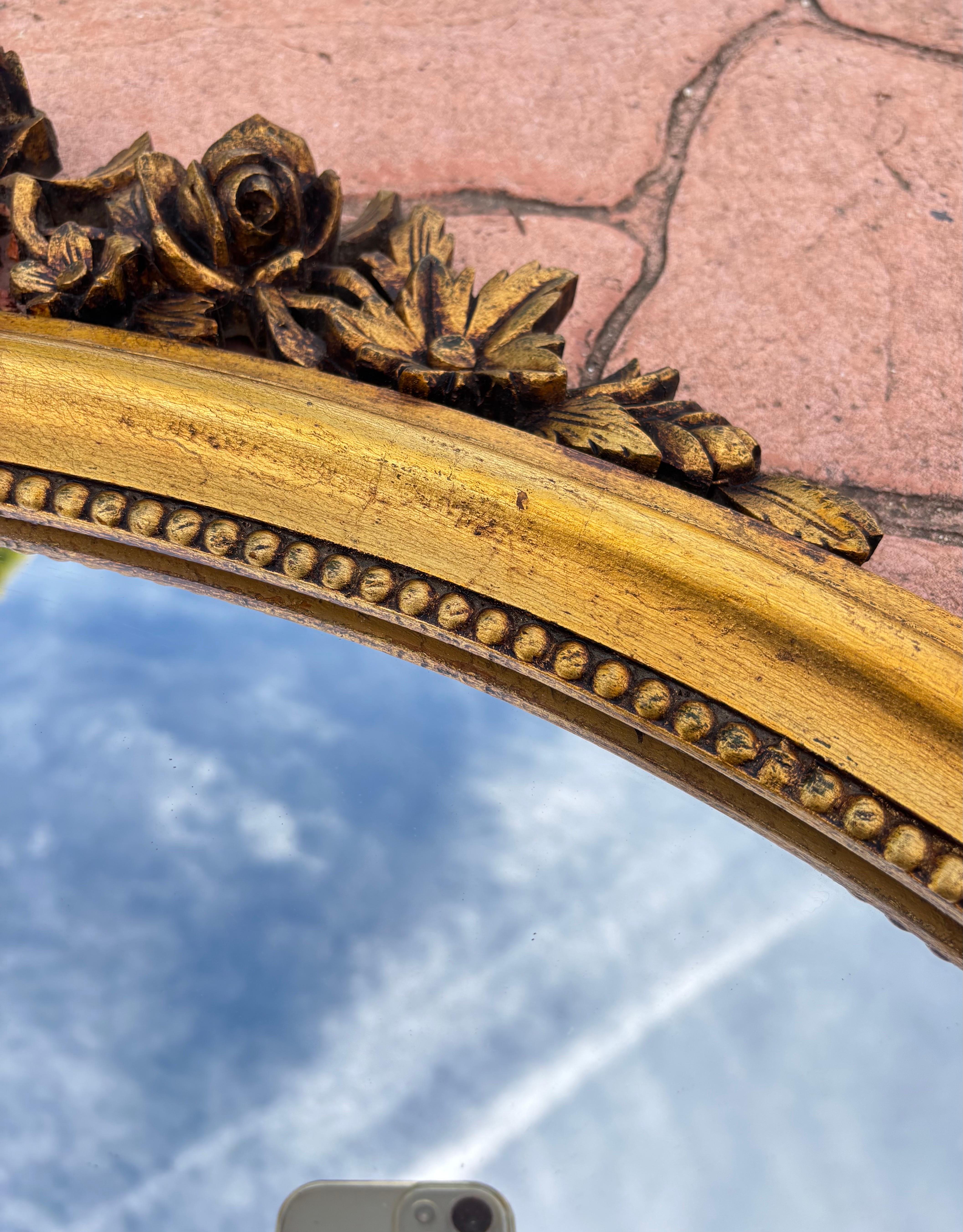 Feuille d'or Miroir mural ovale des années 1940 avec cadre doré et décoration florale de style Louis XVI en vente