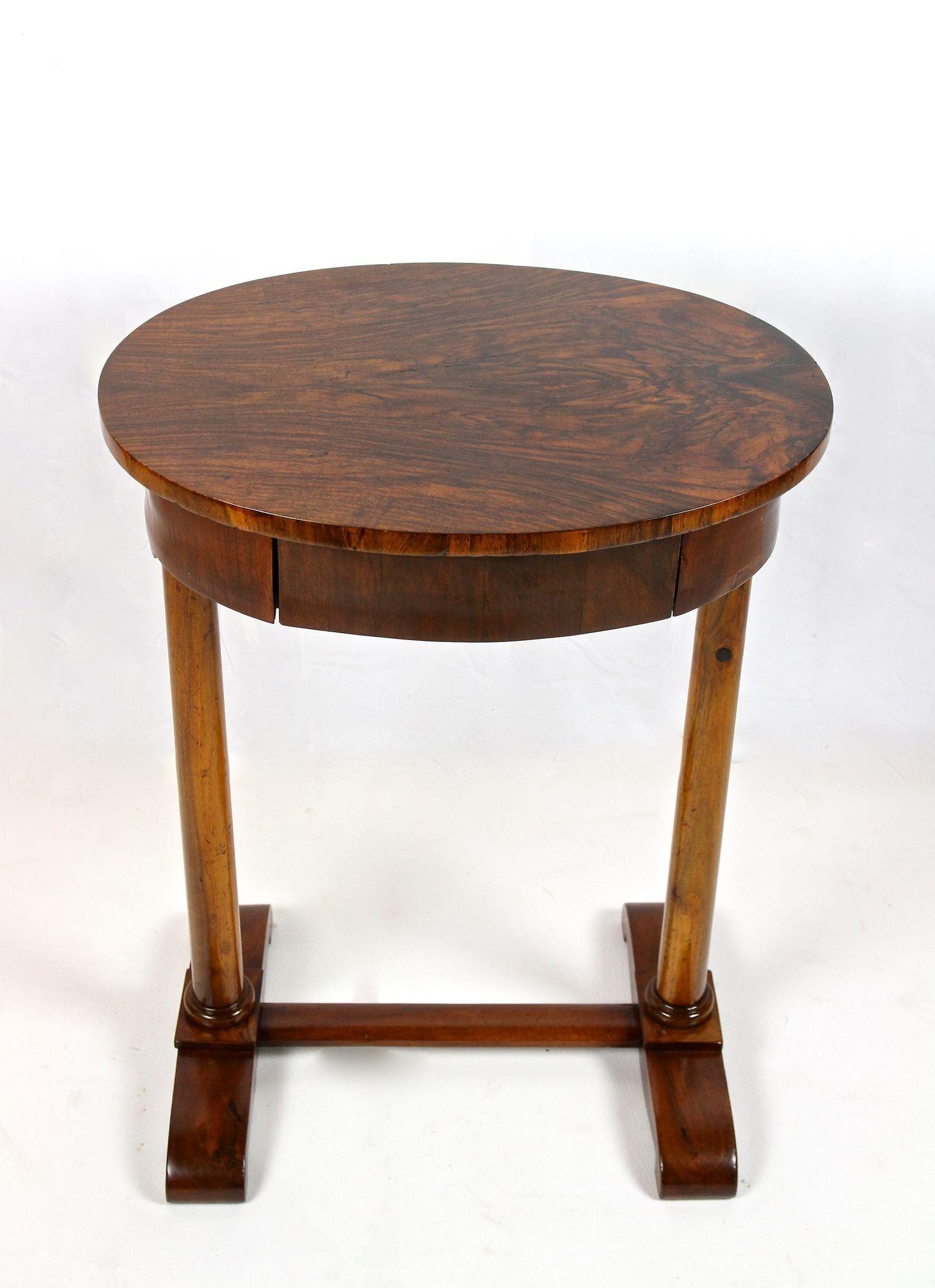Charming oval 19th century nutwood side table coming from the famous Biedermeier period in Austria around 1830. With an age of over 190 years this charming nutwood side table is still an eye-catcher and provides a small center drawer, divided into
