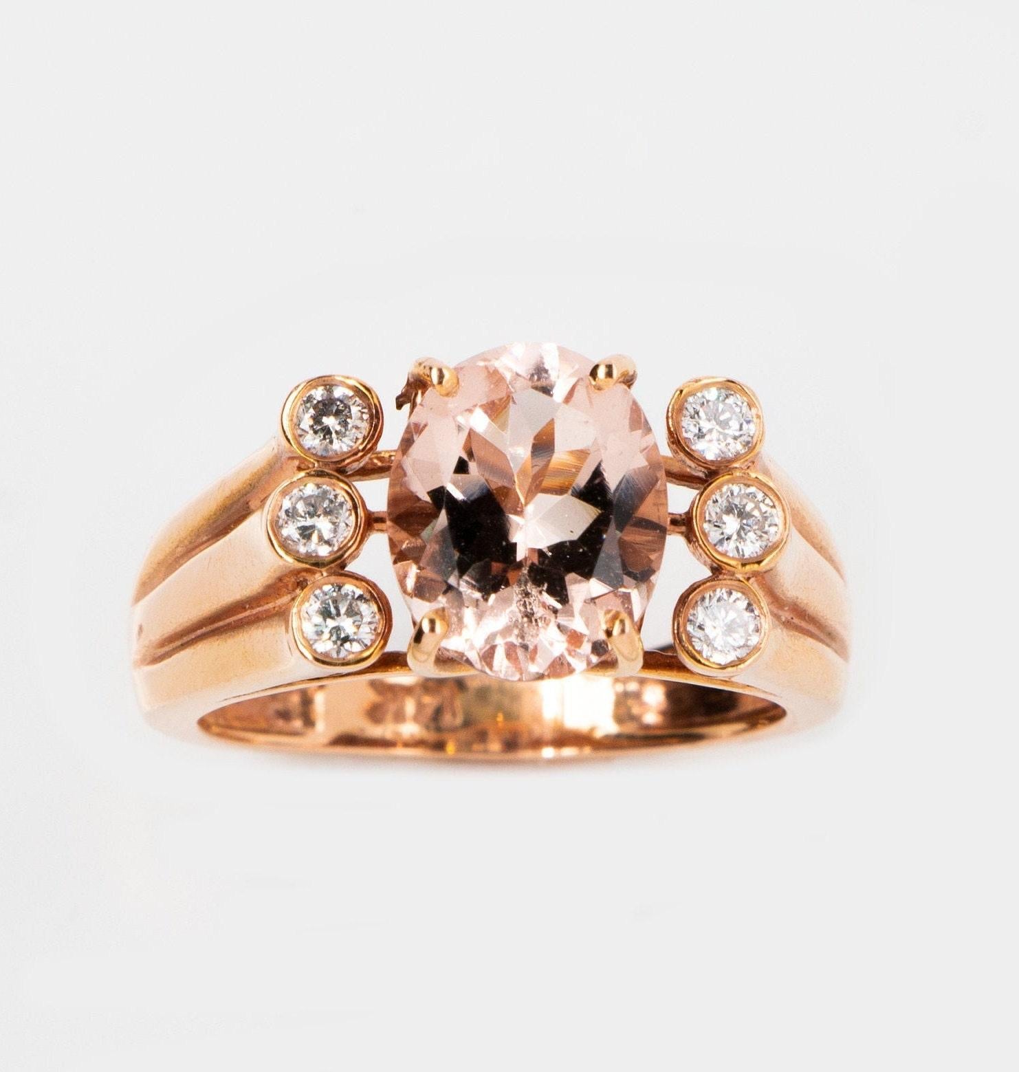 This is a unique and magnificent natural morganite and diamond  ring set in solid 14K rose gold. The vivid 10X8MM 2.40 carat Morganite oval has an excellent peachy pink color (AAA quality gem) and is set on top of a gorgeous curved band that has 6