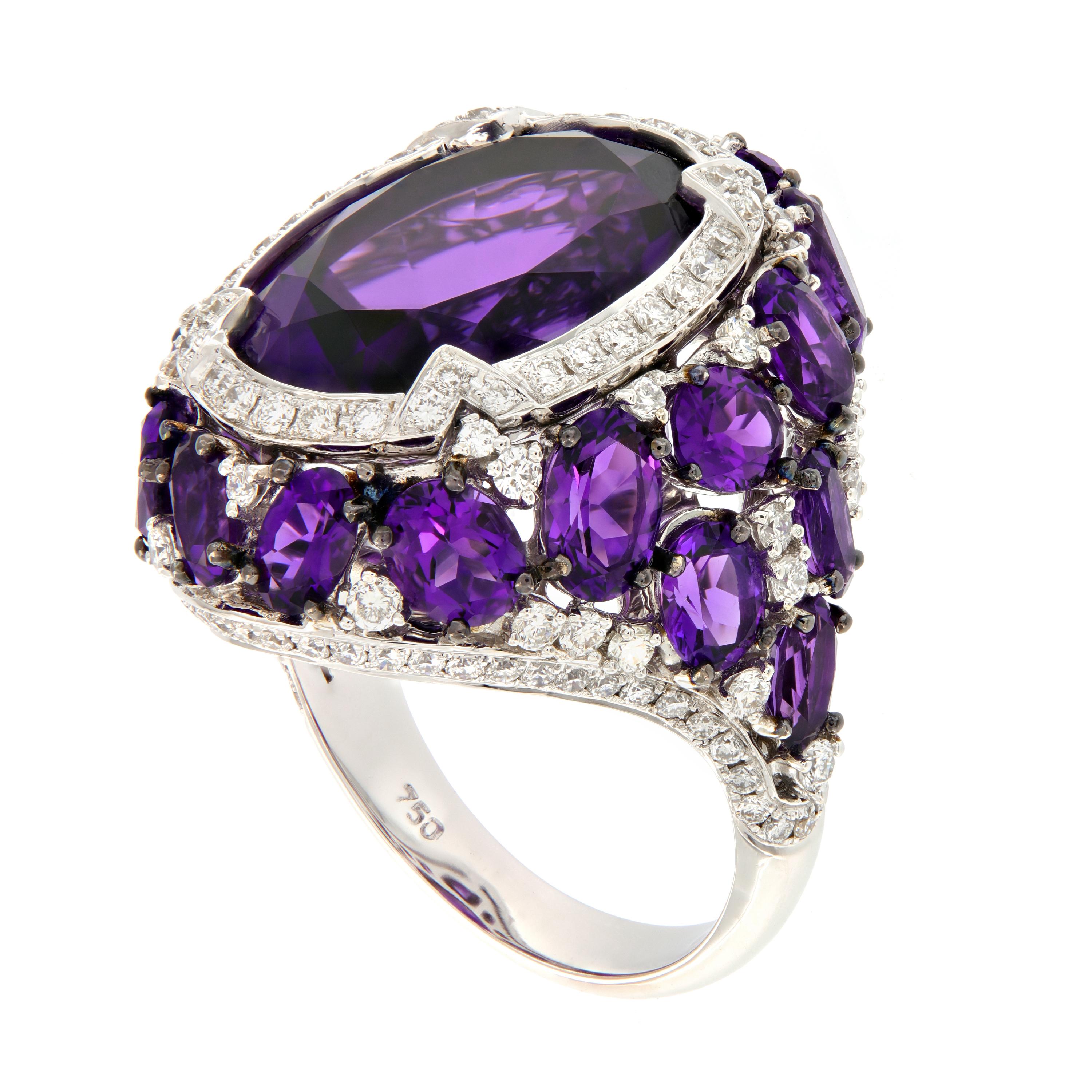 A beautiful deep purple oval-cut amethyst is artfully enhanced by 21 smaller oval amethysts and over one carat of diamonds. This exquisite cocktail ring is beautifully crafted in Switzerland for CAMPANELLI & PEAR 18k white gold. 
Ring size is 6.25.