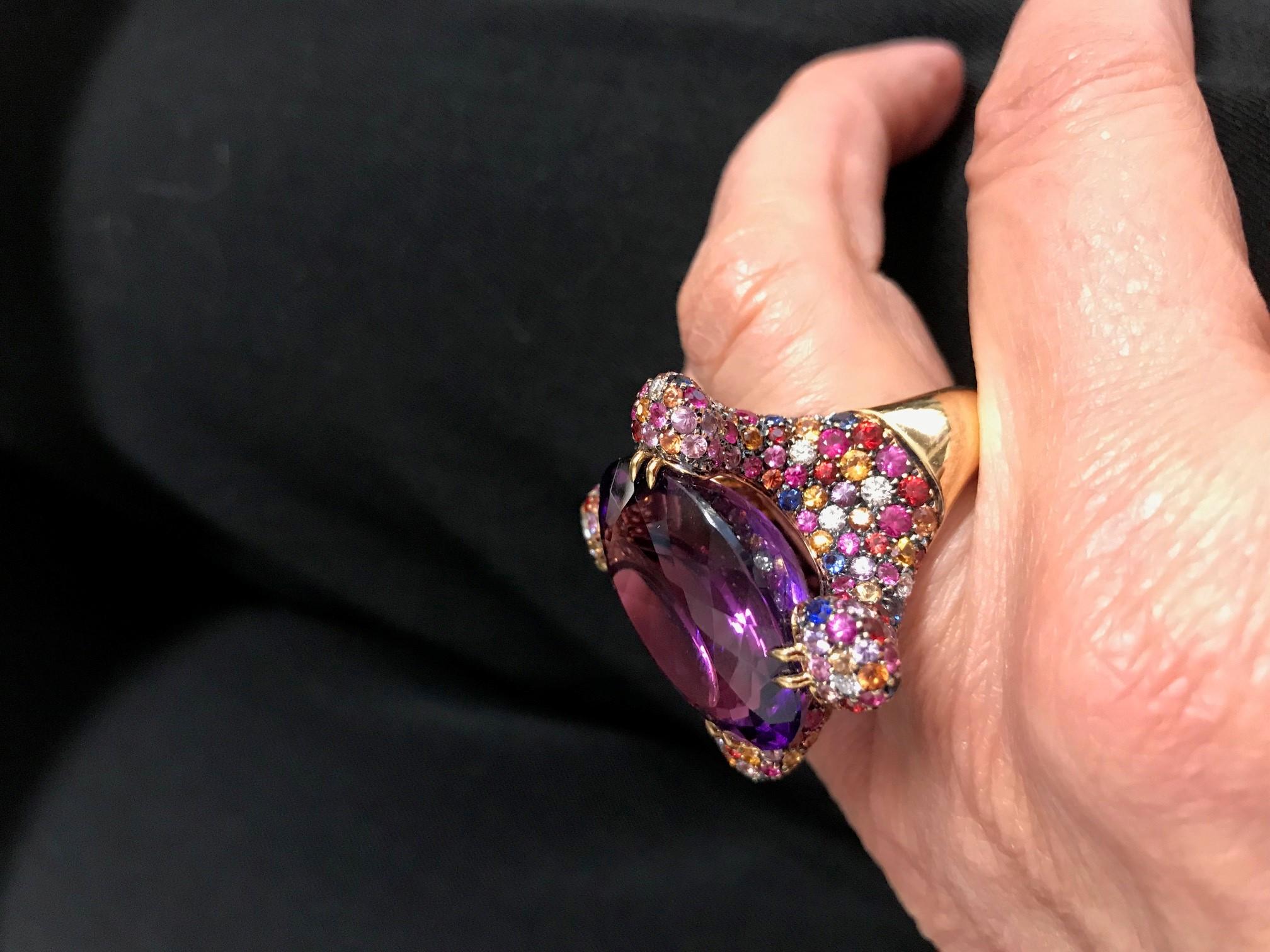 Handcrafted in Margherita Burgener family workshop, Valenza,  Italy, in 18kt rose gold, the colorful cocktail ring is centering a stunning February birthstone Amethyst.  
Surrounded by a pavè of sapphires of several colors, spotted by diamonds, it