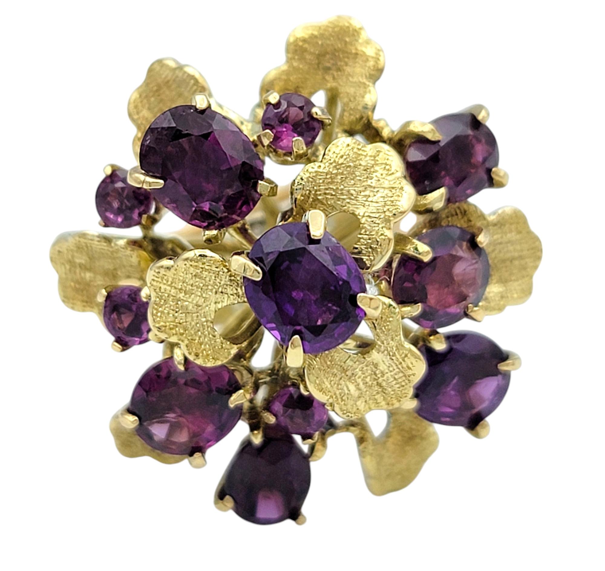 Taille de l'anneau : 6.5

Cette bague à grenat époustouflante est un mélange saisissant de couleur audacieuse et de design complexe, sertie dans la chaleur de l'or jaune 14 carats. Au cœur de la pièce, des grenats ovales de couleur rouge-pourpre
