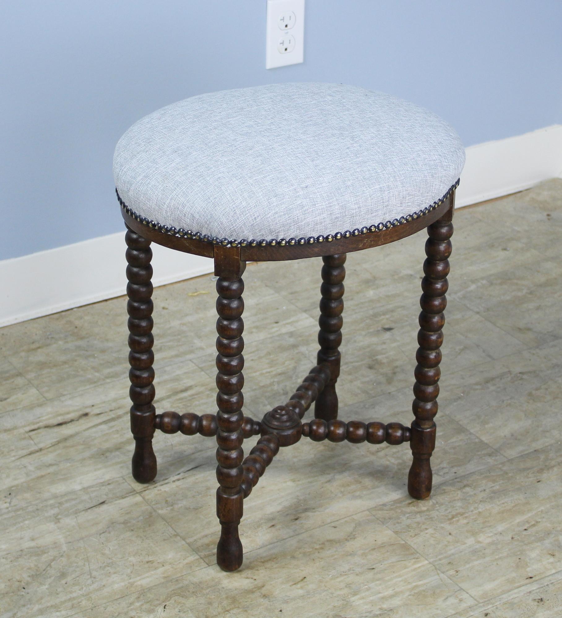 An eye-catching bobbin legged stool, newly upholstered in gray linen. Nice comfortable height provides good extra seating in any room. If you need more than one, take a look at our round stool, similarly upholstered.