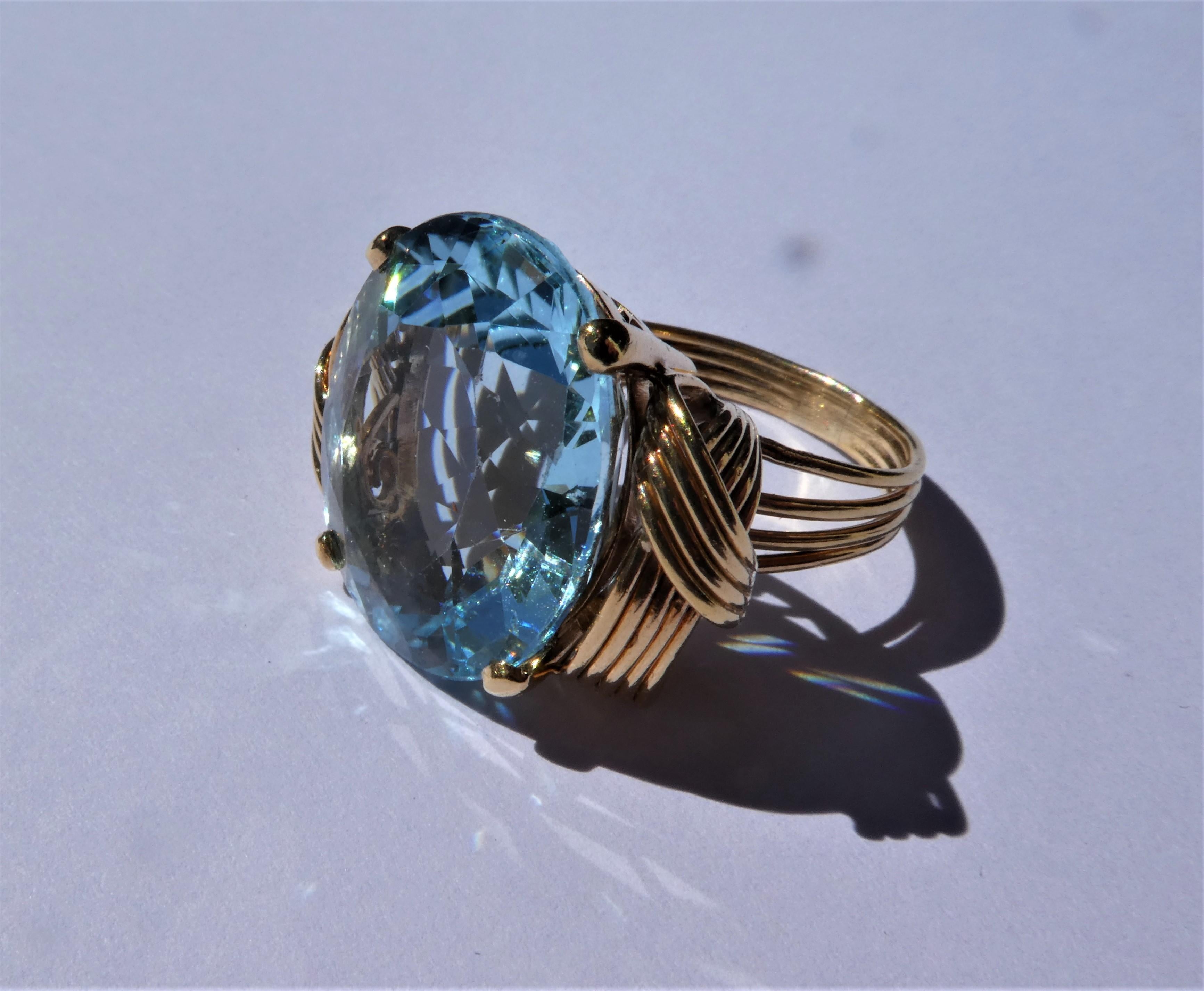 This cocktail ring was crafted in the 1950s in the United States in 14 karat rose gold. On the side it is decorated with a braided rilled band. The aquamarine of circa 20 carat has a vibrant strong blue colour in a slightly oval cut with the