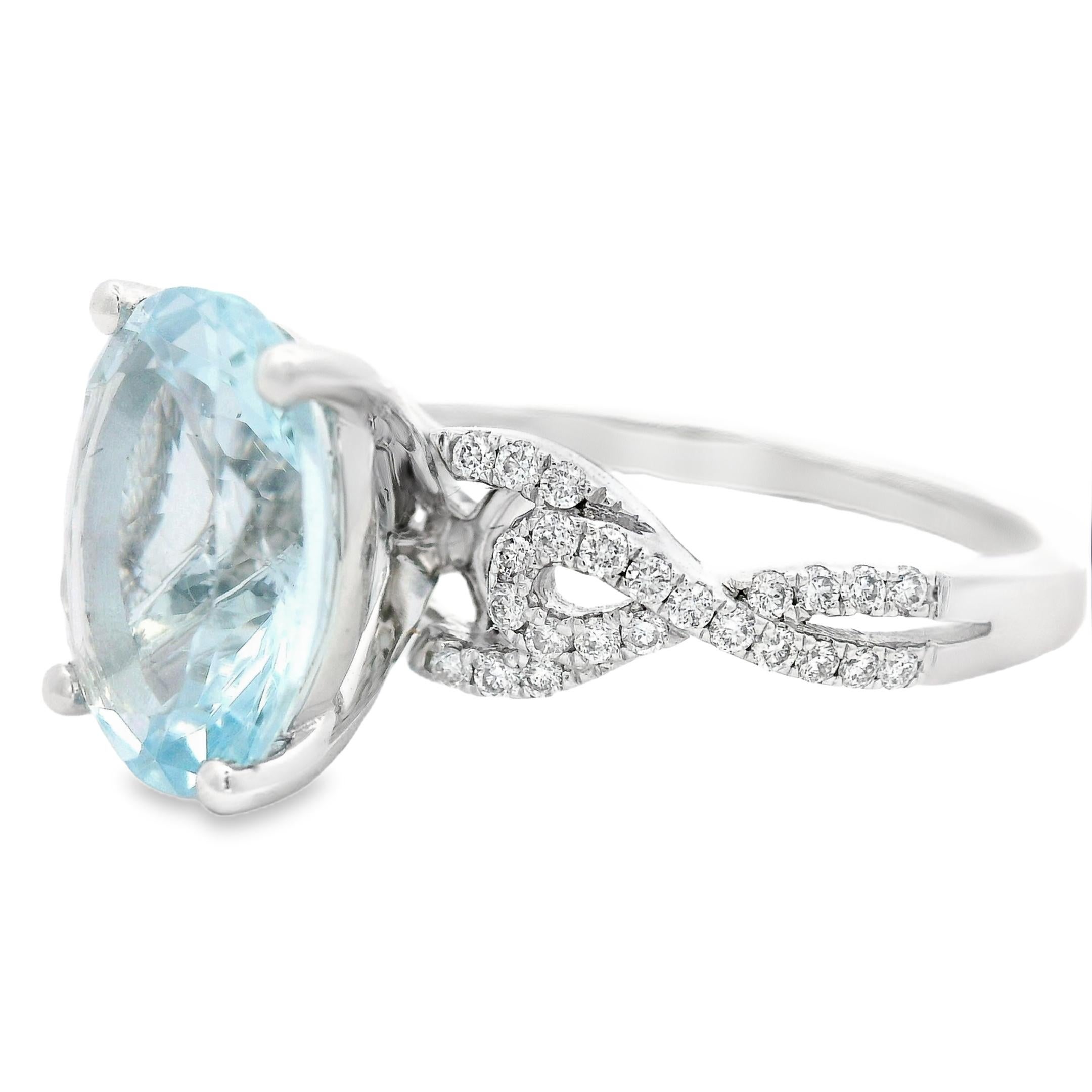 This elegant cocktail ring features a 2.80-carat oval aquamarine, measuring 11mm x 9mm, held in a four-prong setting designed to maximize its light return and airy blue color. The center stone floats above an intricate diamond-accented band, where