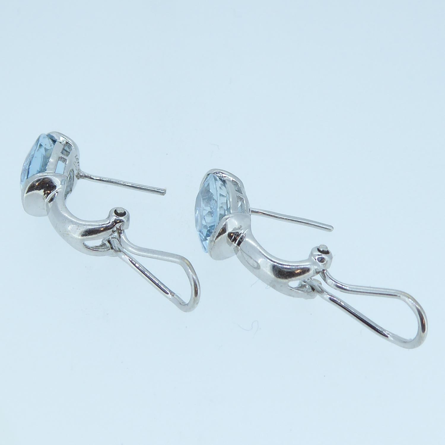 Two beautiful blue aquamarines have been used to create these stud style earrings.  The aquamarines are faceted and held in a white gold part rub over set mount and designed to sit neatly on the ear in a stud fashion.  Beneath each aquamarine is a