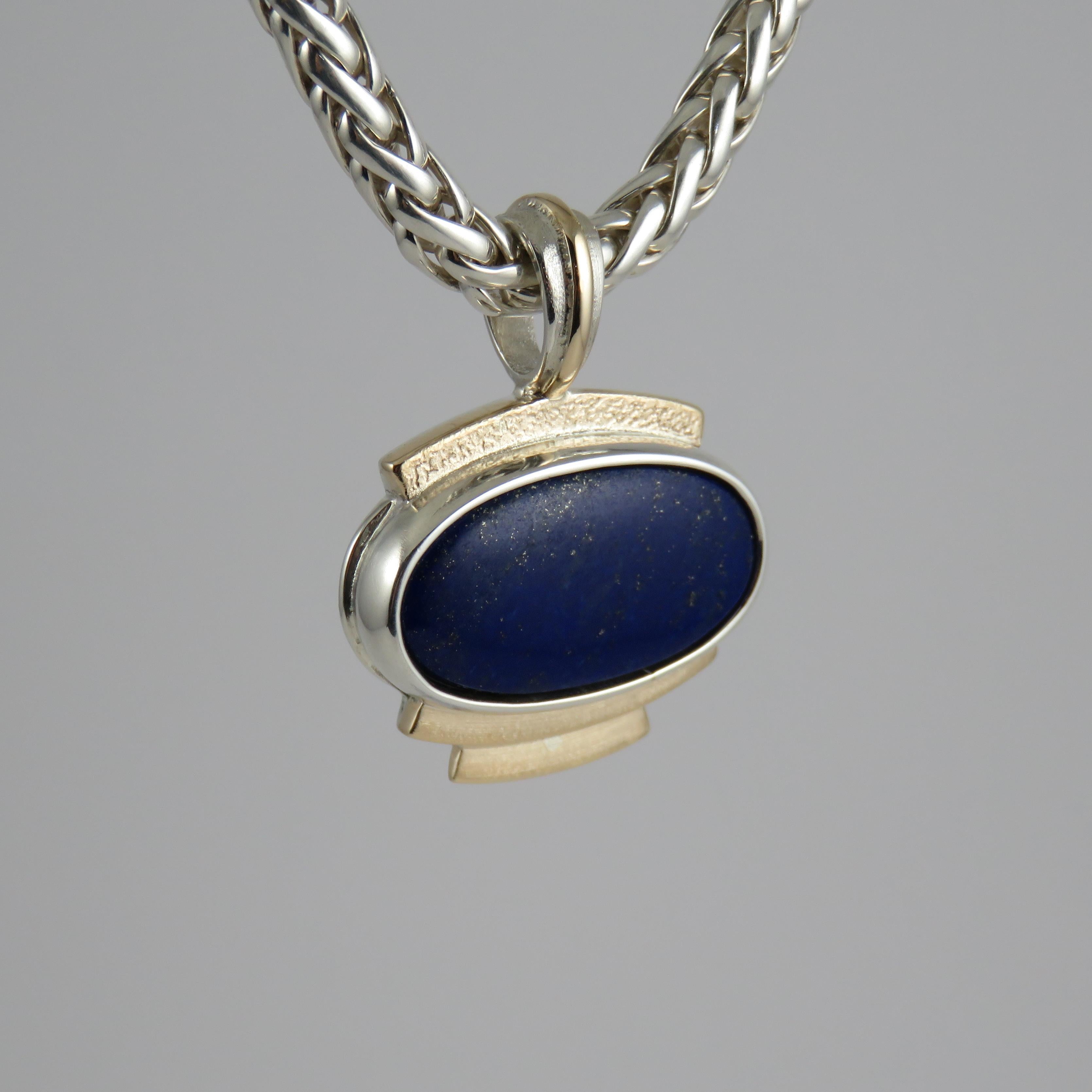 The lapis lazuli stone, totaling 29.46 carats takes center stage in this beautiful handmade pendant in a rub over cabochon setting, which is a classic and timeless style that allows the violet blue colored stone to shine with the pyrite and calcite
